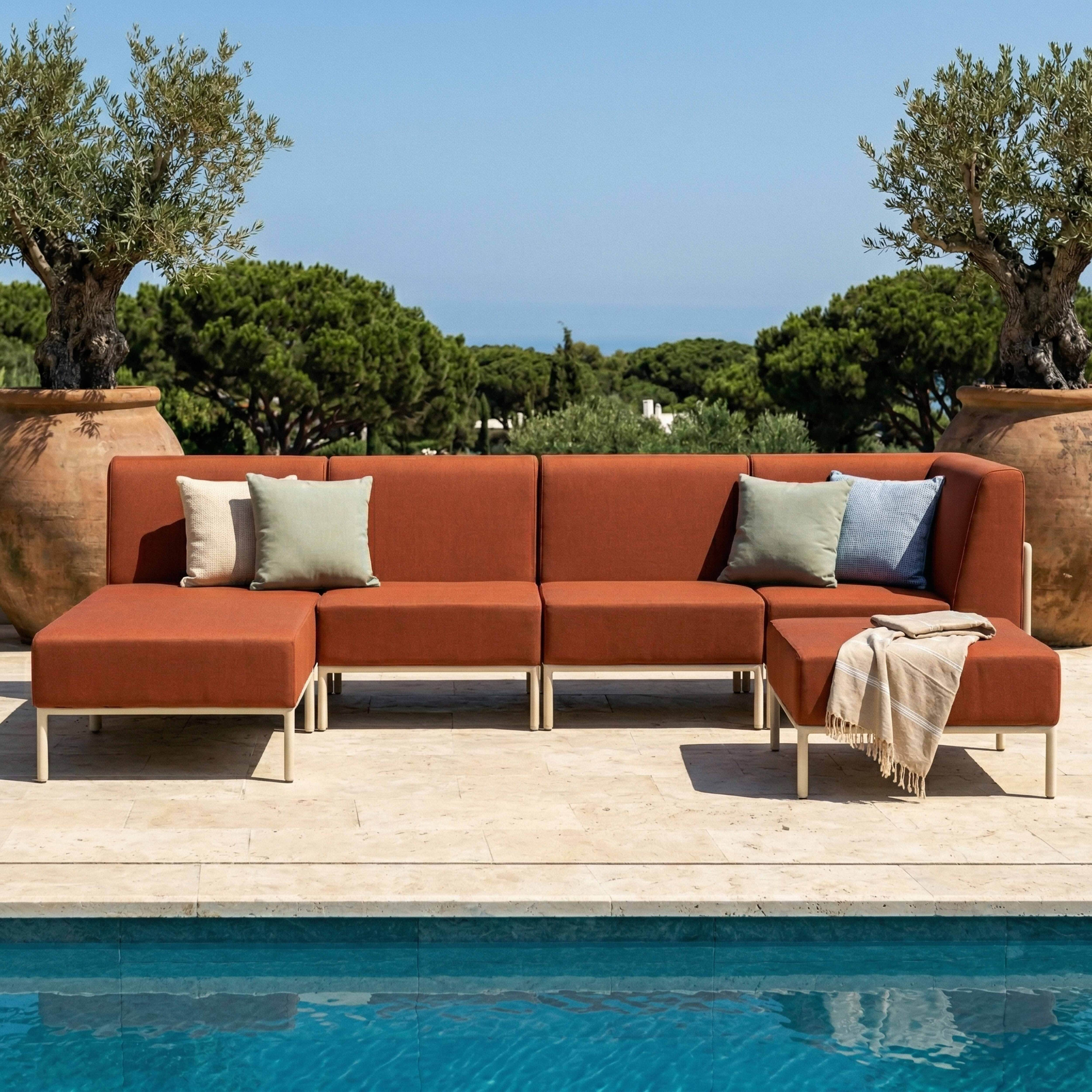 Orange Lounge-Möbel am Pool mit Olivenbäumen und viel Grün im Hintergrund.