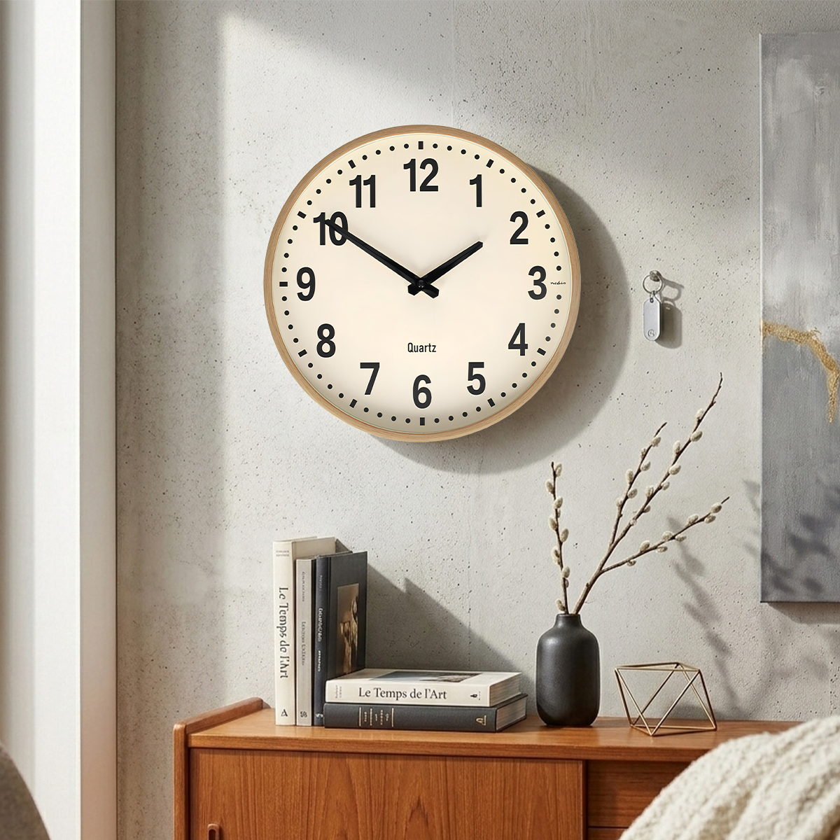 Eine Wanduhr mit Holzrahmen hängt an einer Betonwand. Bücher und eine Vase stehen auf einem Holzschrank.