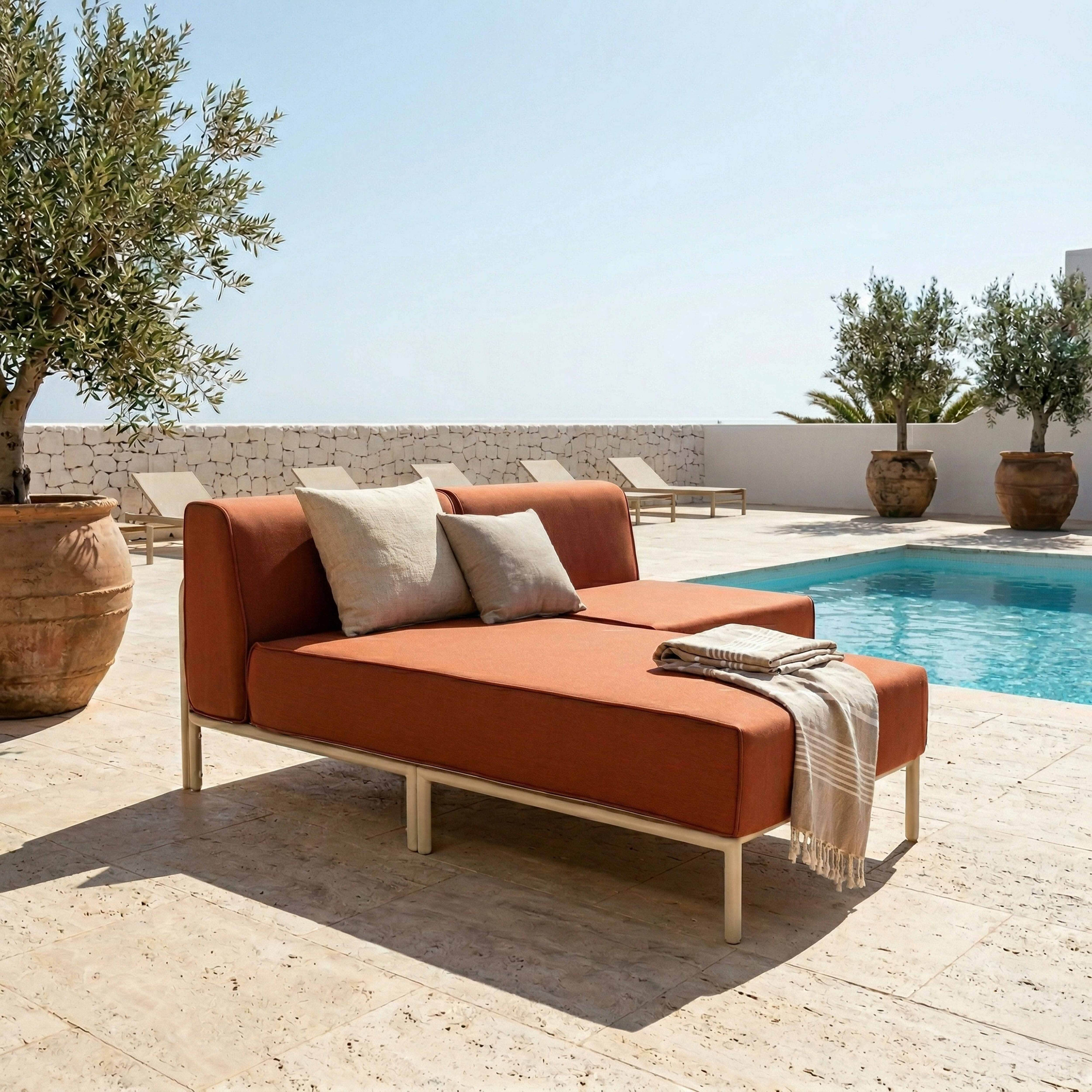 Orange-farbene Lounge-Möbel am Pool mit Olivenbäumen und Liegestühlen im Freien.