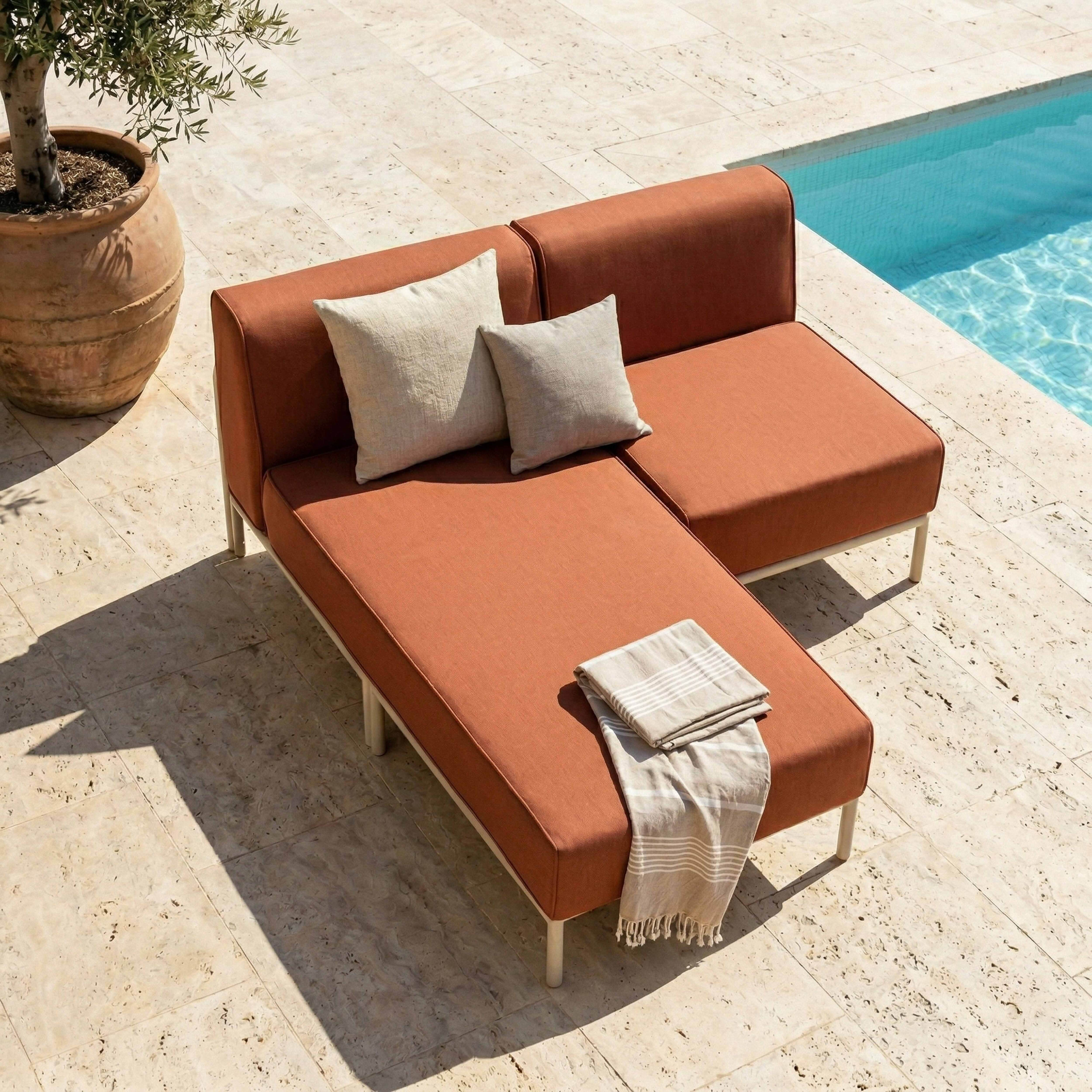 Orange Lounge-Möbel neben einem Pool, mit Kissen und einer Decke.