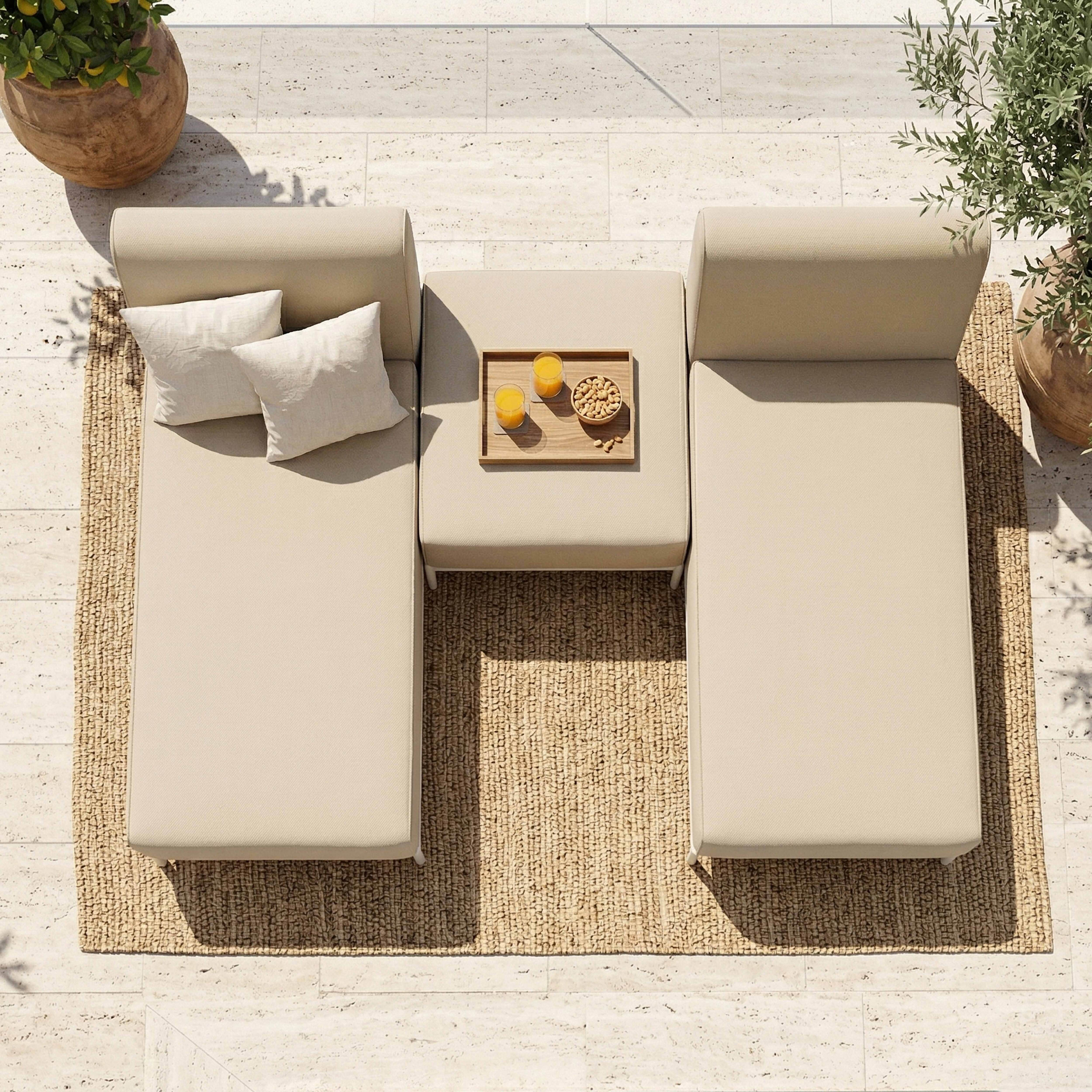 Beige Outdoor-Lounge mit Kissen, Tisch, Getränken und Snacks auf einem Teppich.