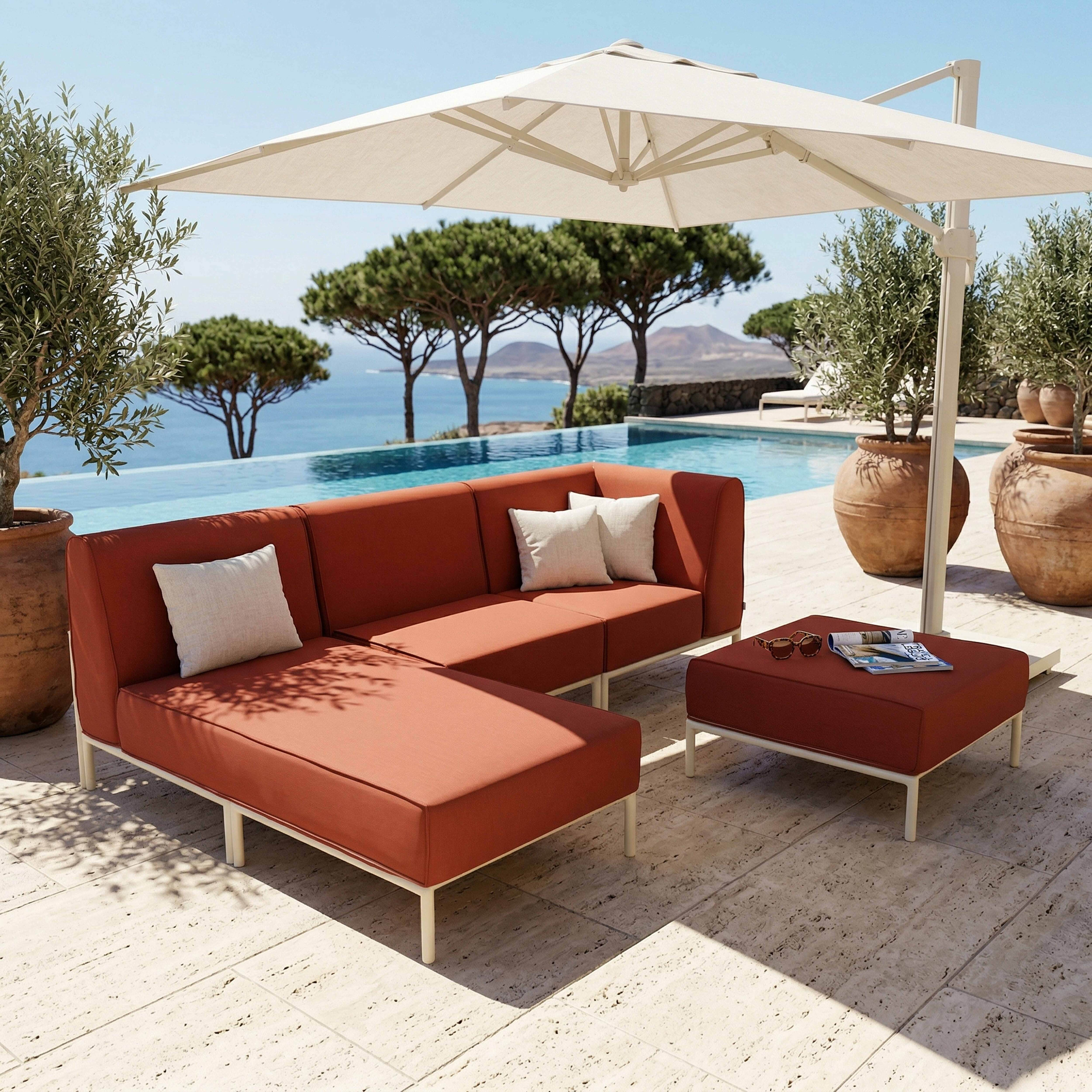 Rote Loungegarnitur mit Sonnenschirm am Pool mit Meerblick.