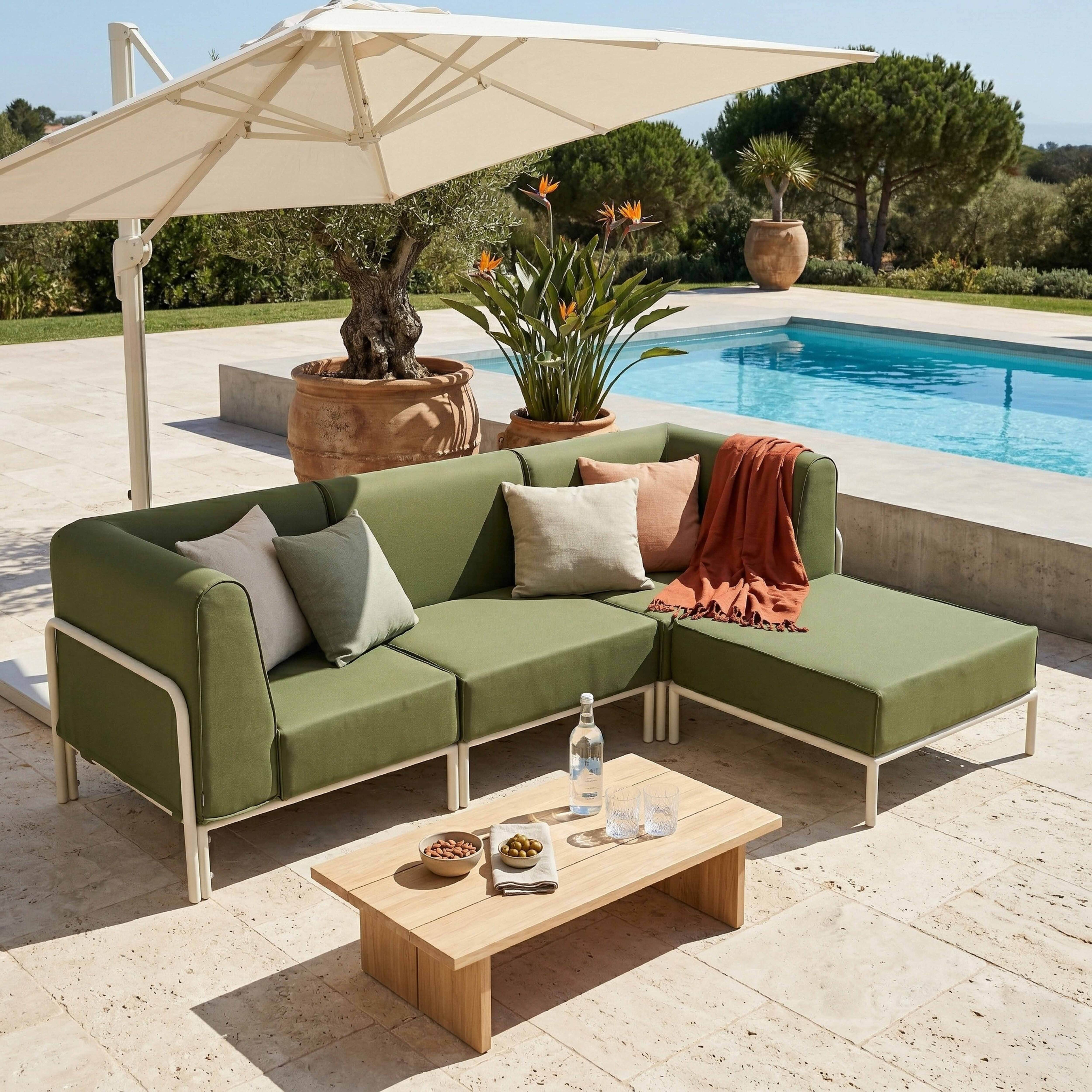 Grünes Ecksofa mit Beistelltisch, Pool und Sonnenschirm im Freien.
