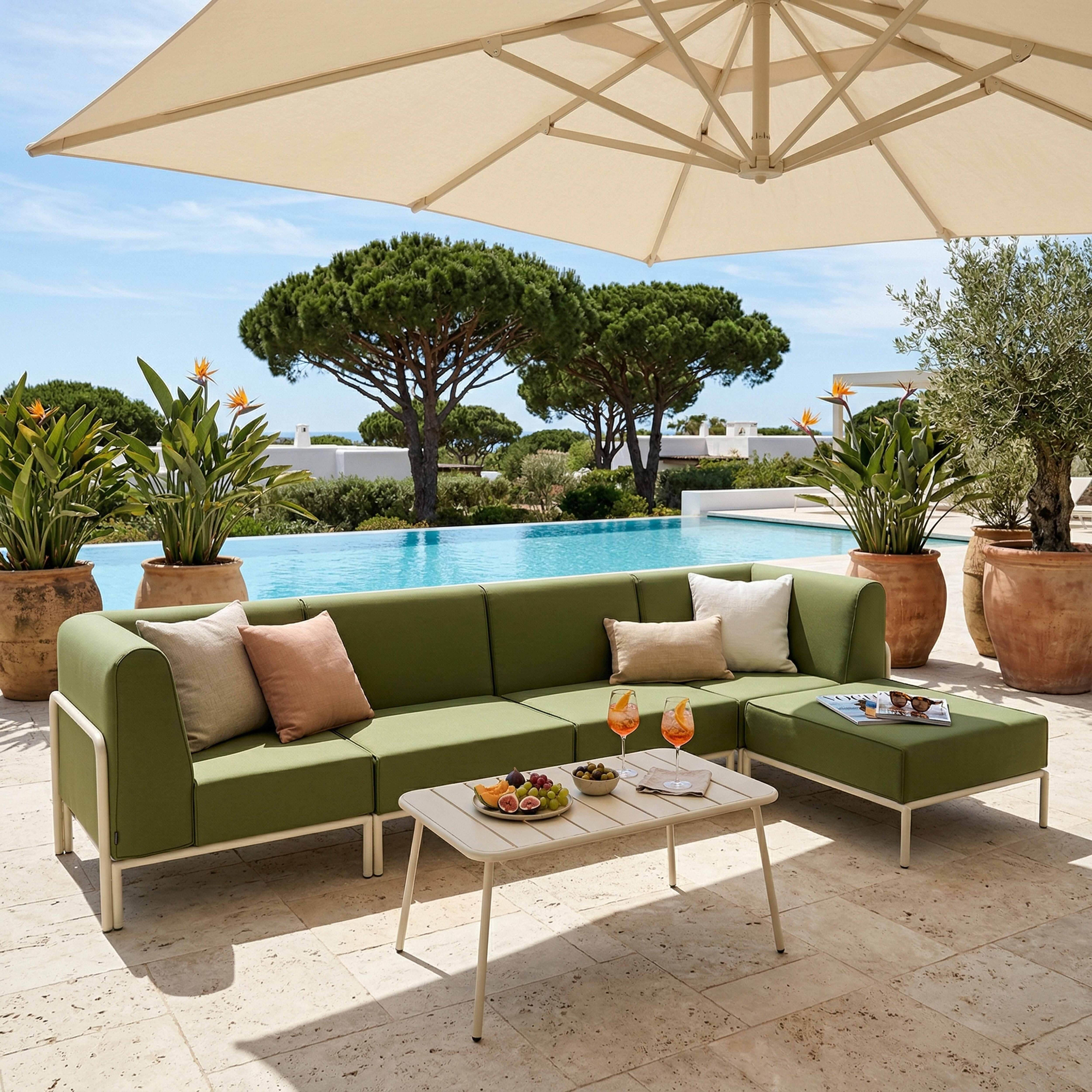 Grüne Lounge-Möbel am Pool mit Obst und Getränken unter Sonnenschirm.