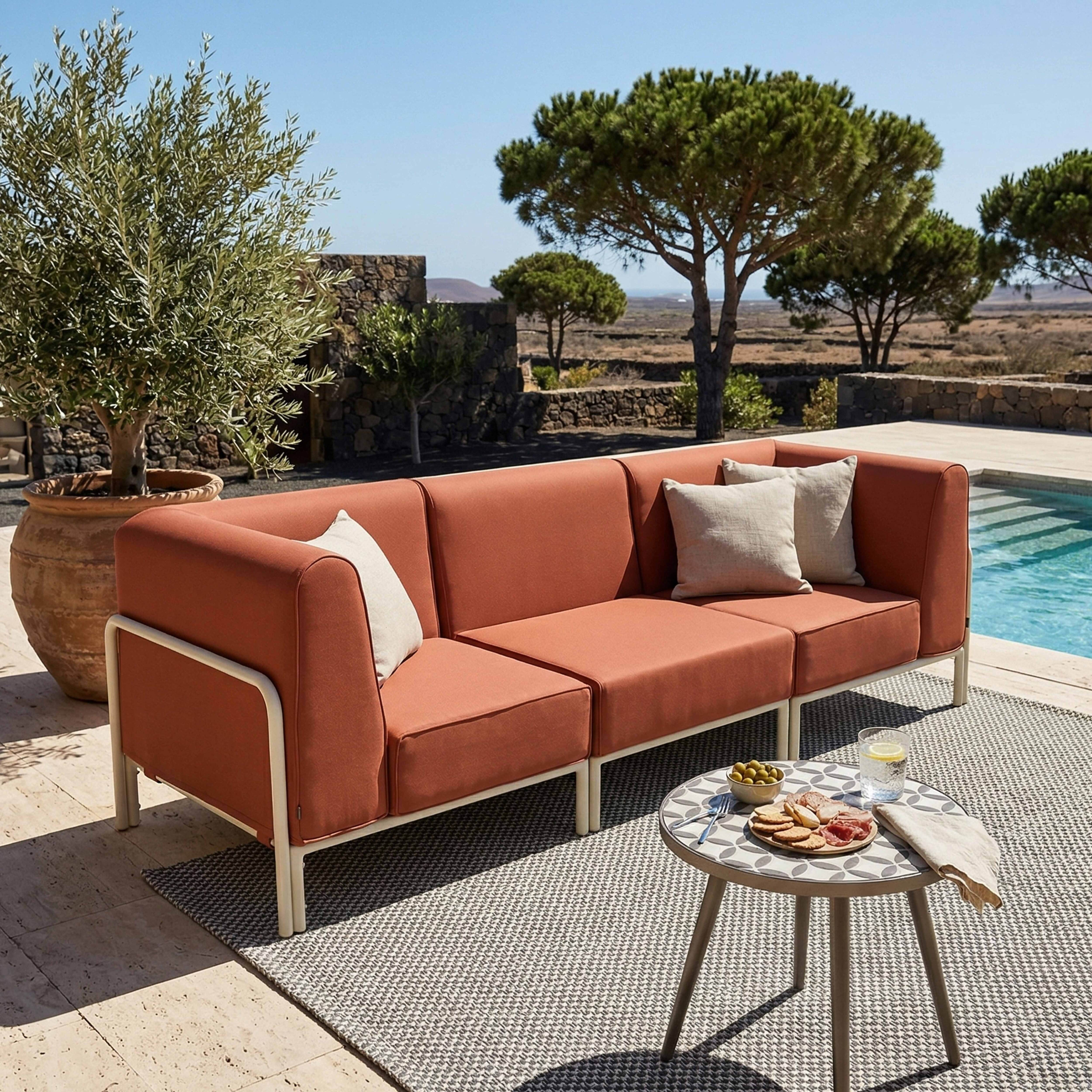 Außenlounge mit orangefarbenem Sofa, Tisch mit Snacks, Pool und Bäumen.