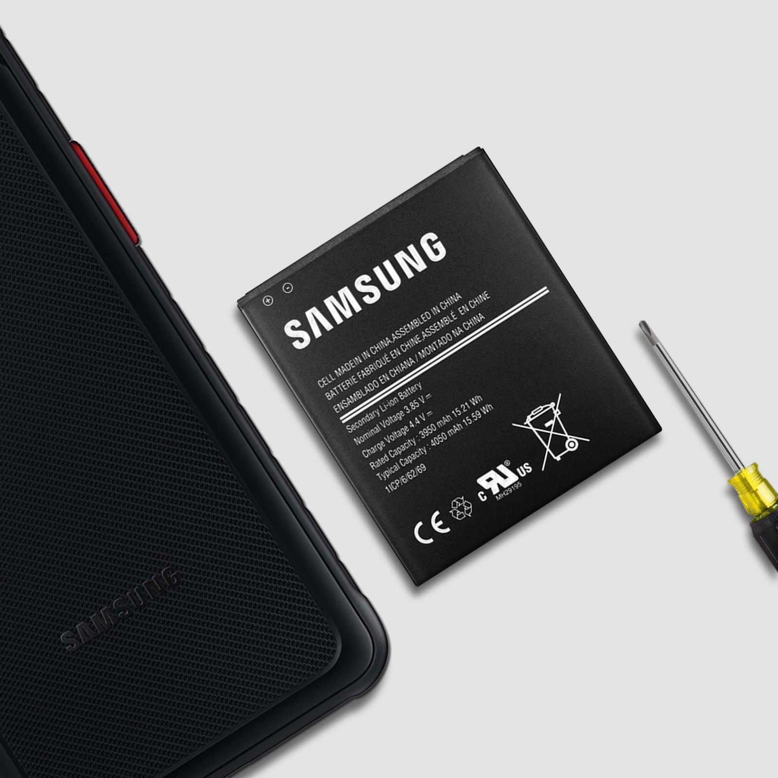 Batteria Samsung, custodia per telefono e cacciavite su sfondo grigio.