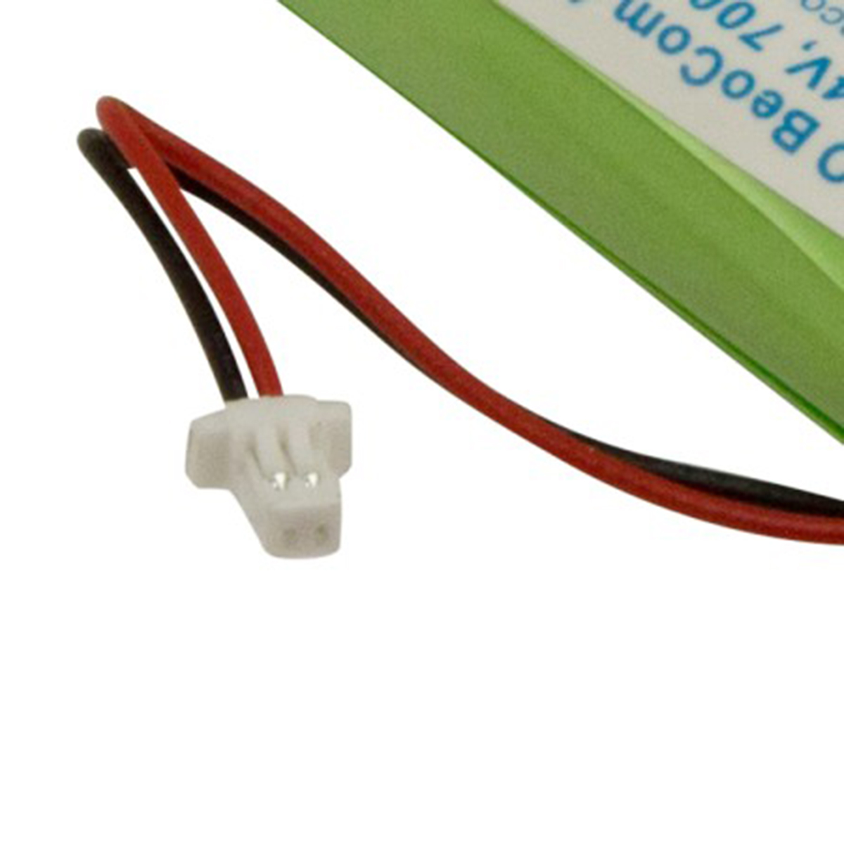 Ein weißer Stecker mit roten und schwarzen Kabeln, neben einer grünen Batterie.