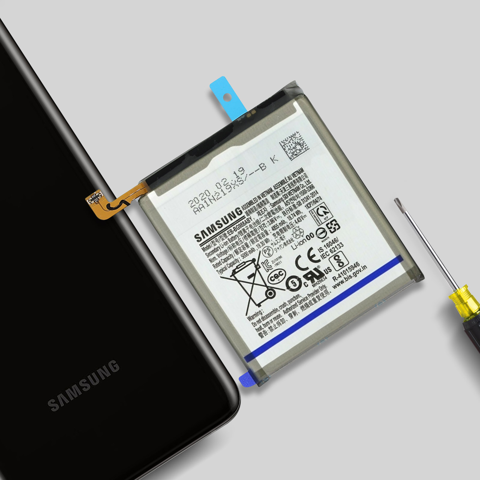 Une batterie Samsung repose à côté d'un smartphone noir et d'un tournevis.