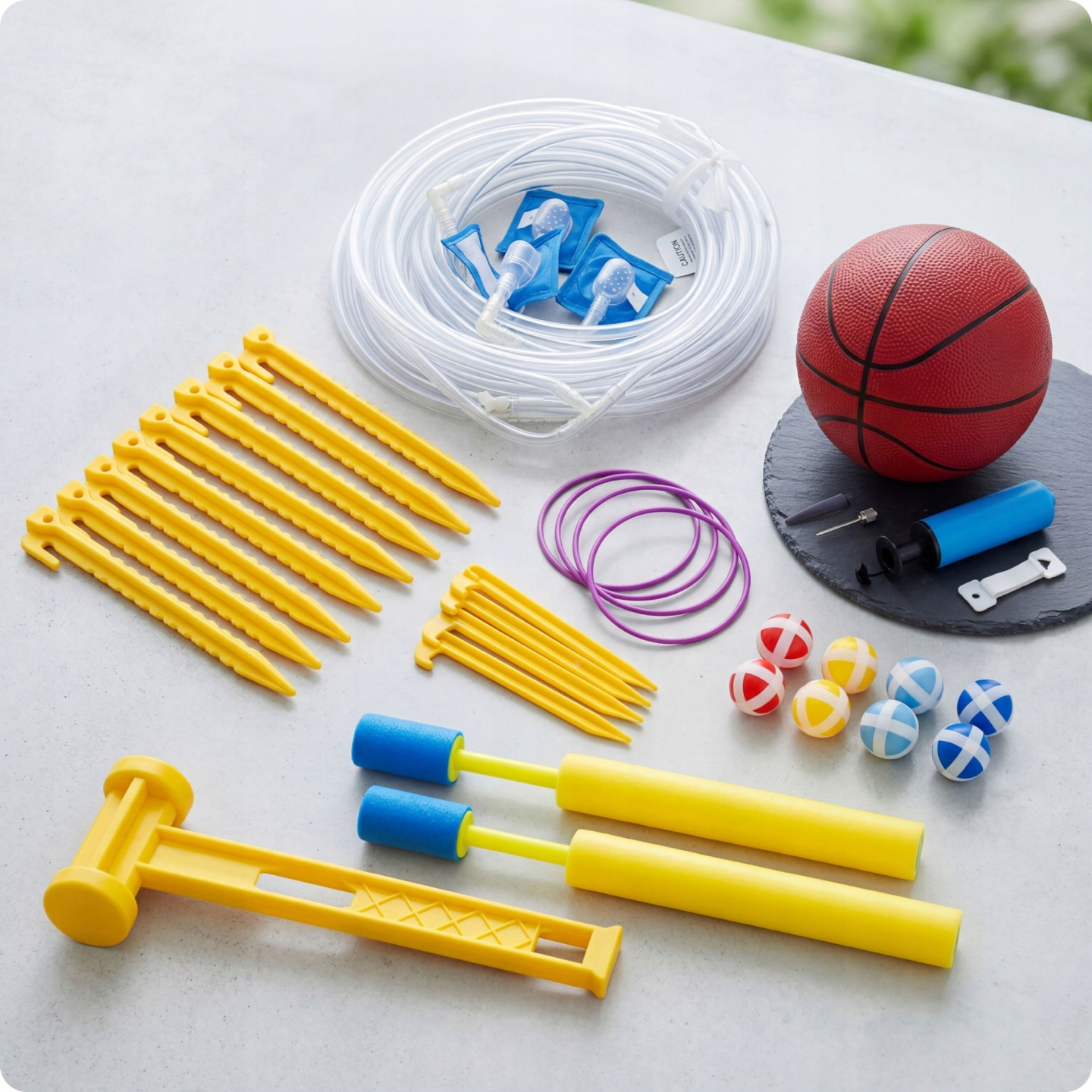 Gelbe Heringe, lila Ringe, Spielzeugbälle, Pumpe und Basketball ausgelegt.