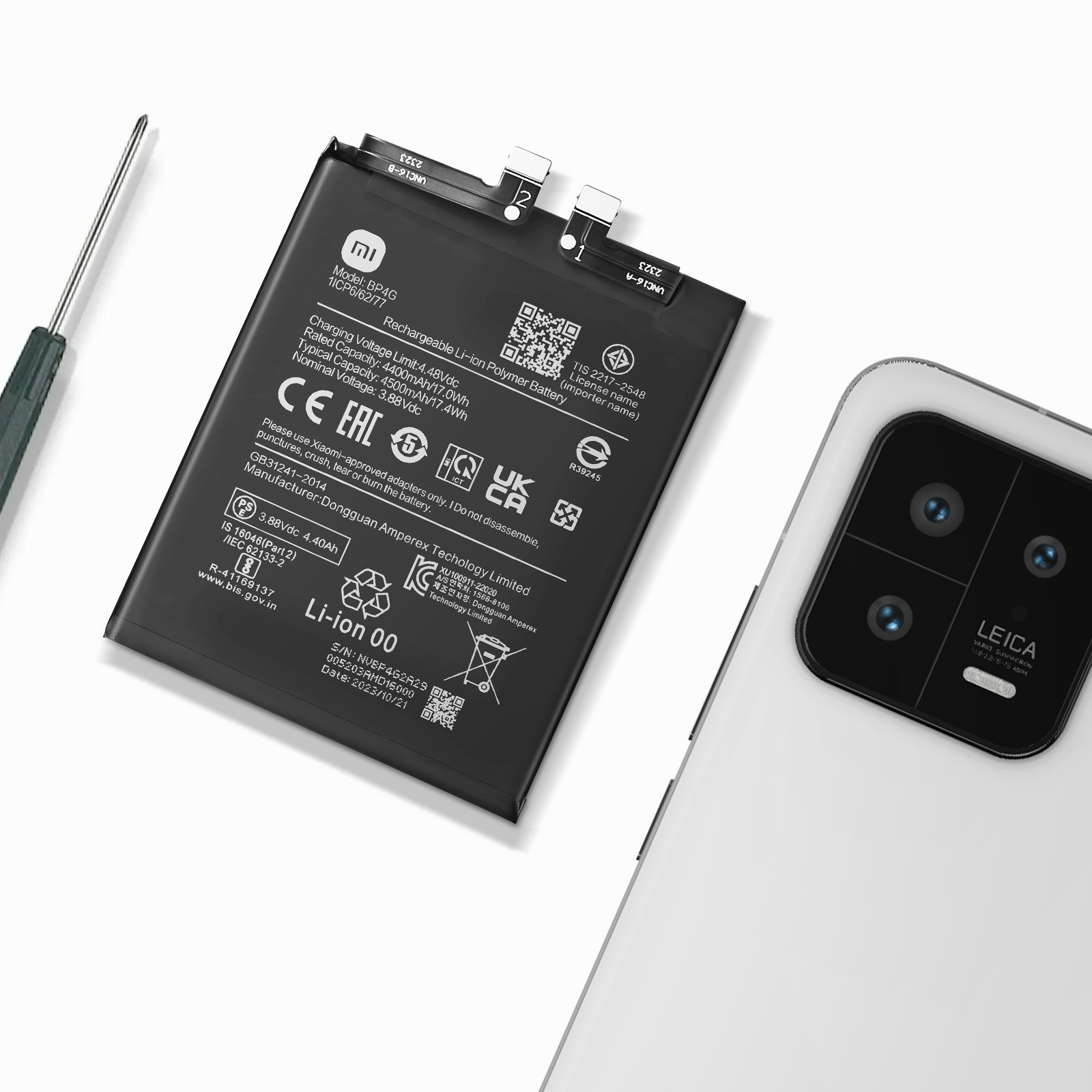 Una batería de smartphone y un destornillador junto a un smartphone.