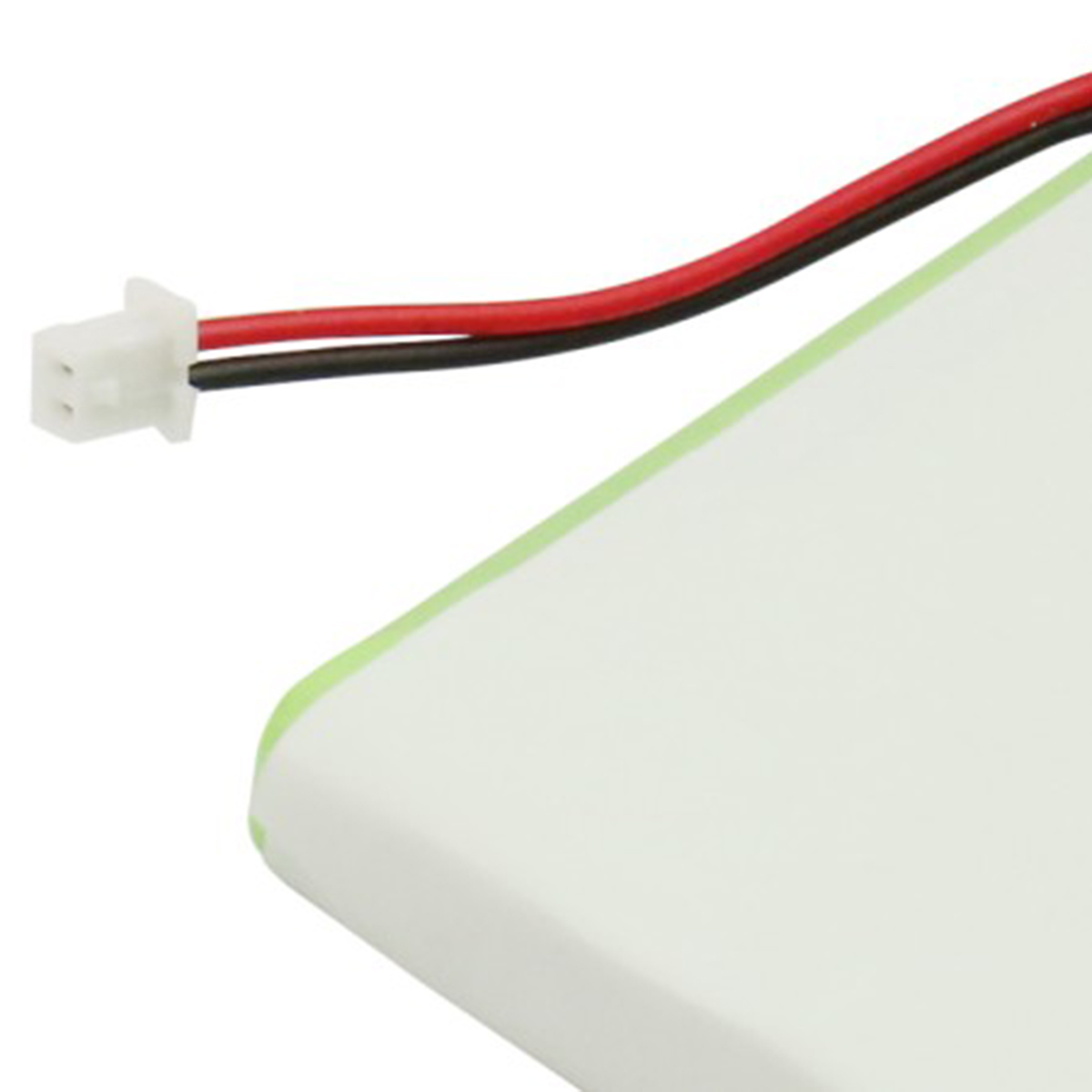 Un connettore bianco con cavi rosso e nero su una superficie verde chiaro.