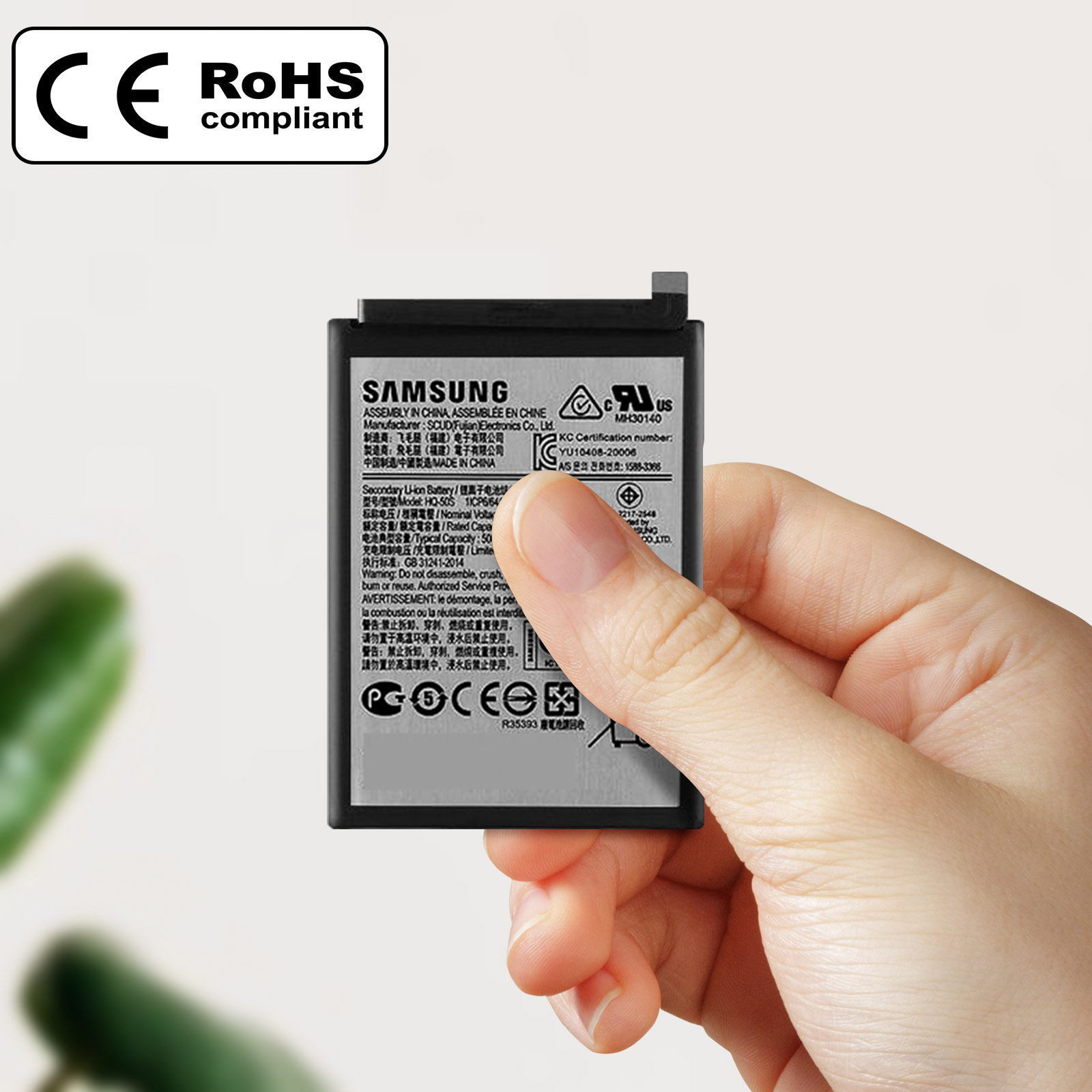 Une main tient une batterie noire Samsung Li-ion avec des étiquettes.