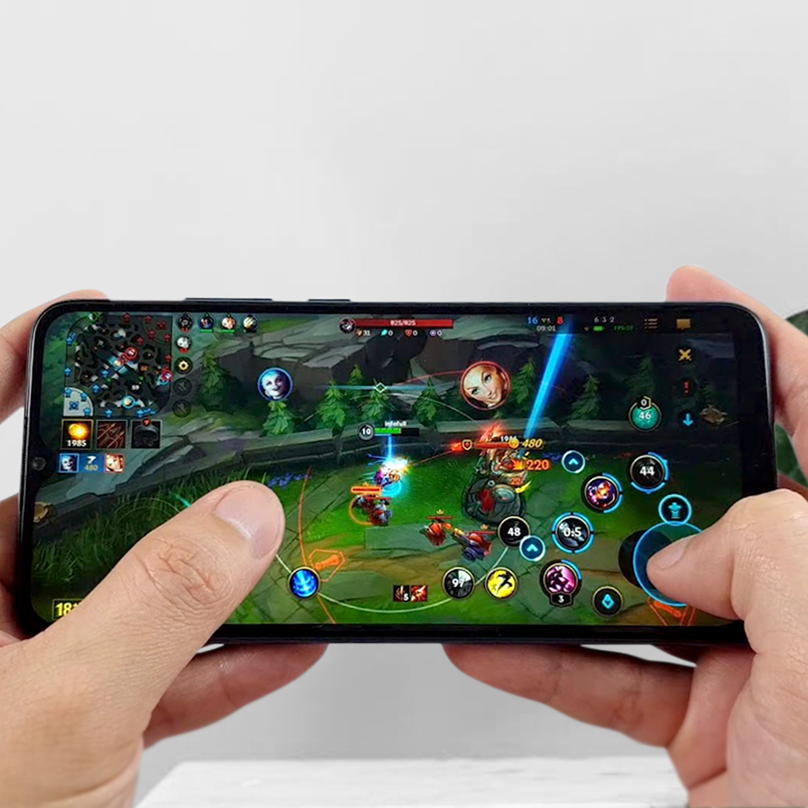 Mains jouant à un jeu mobile, League of Legends, avec joystick virtuel et boutons d'action.