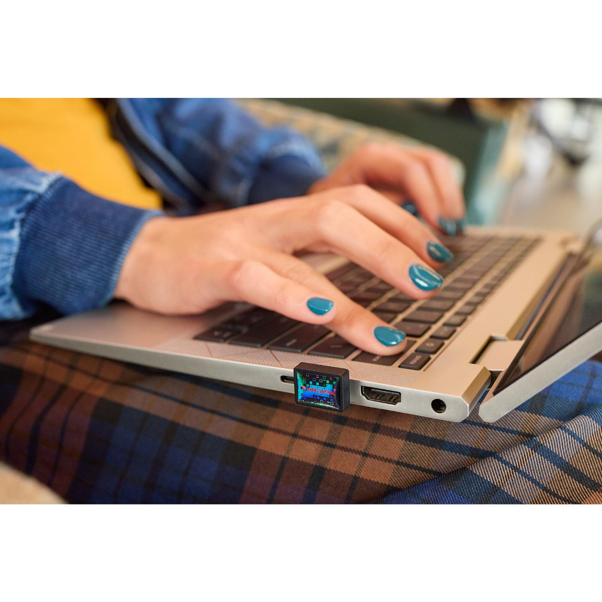 Persona digita su laptop con una piccola chiavetta USB colorata inserita.
