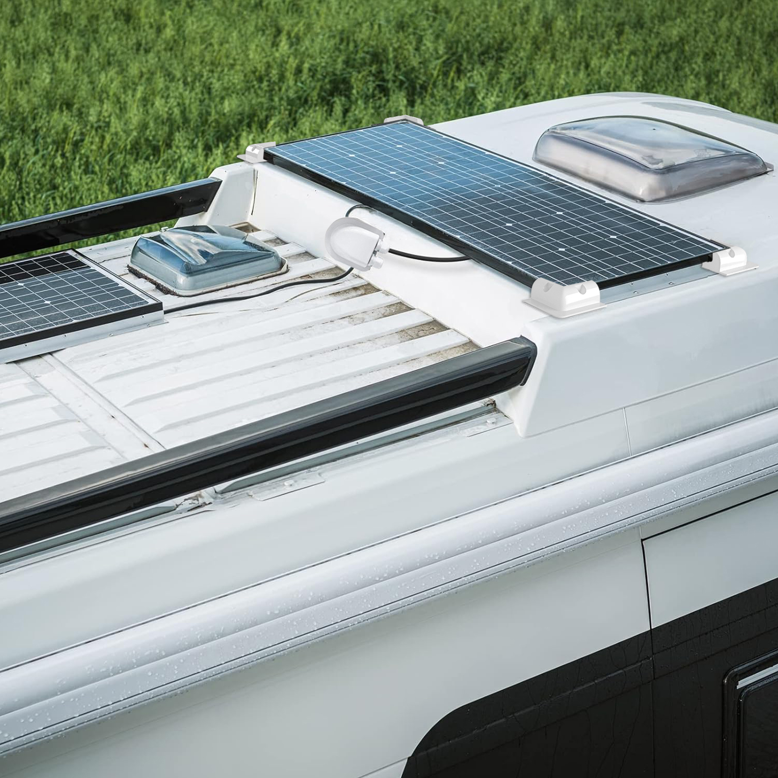 Solarpanel und Dachfenster auf einem weißen Wohnmobil mit grünem Gras im Hintergrund.