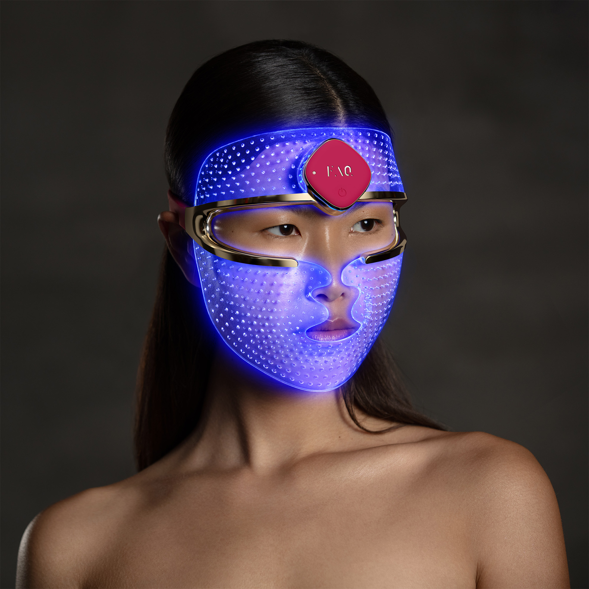 Une femme porte un masque facial LED bleu avec un bouton rouge.