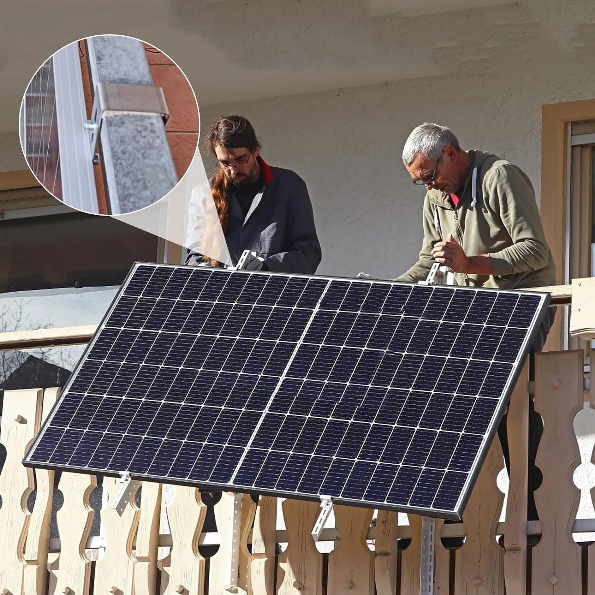 Zwei Männer montieren ein Solarpanel auf einem Balkon mit Holzzaun.