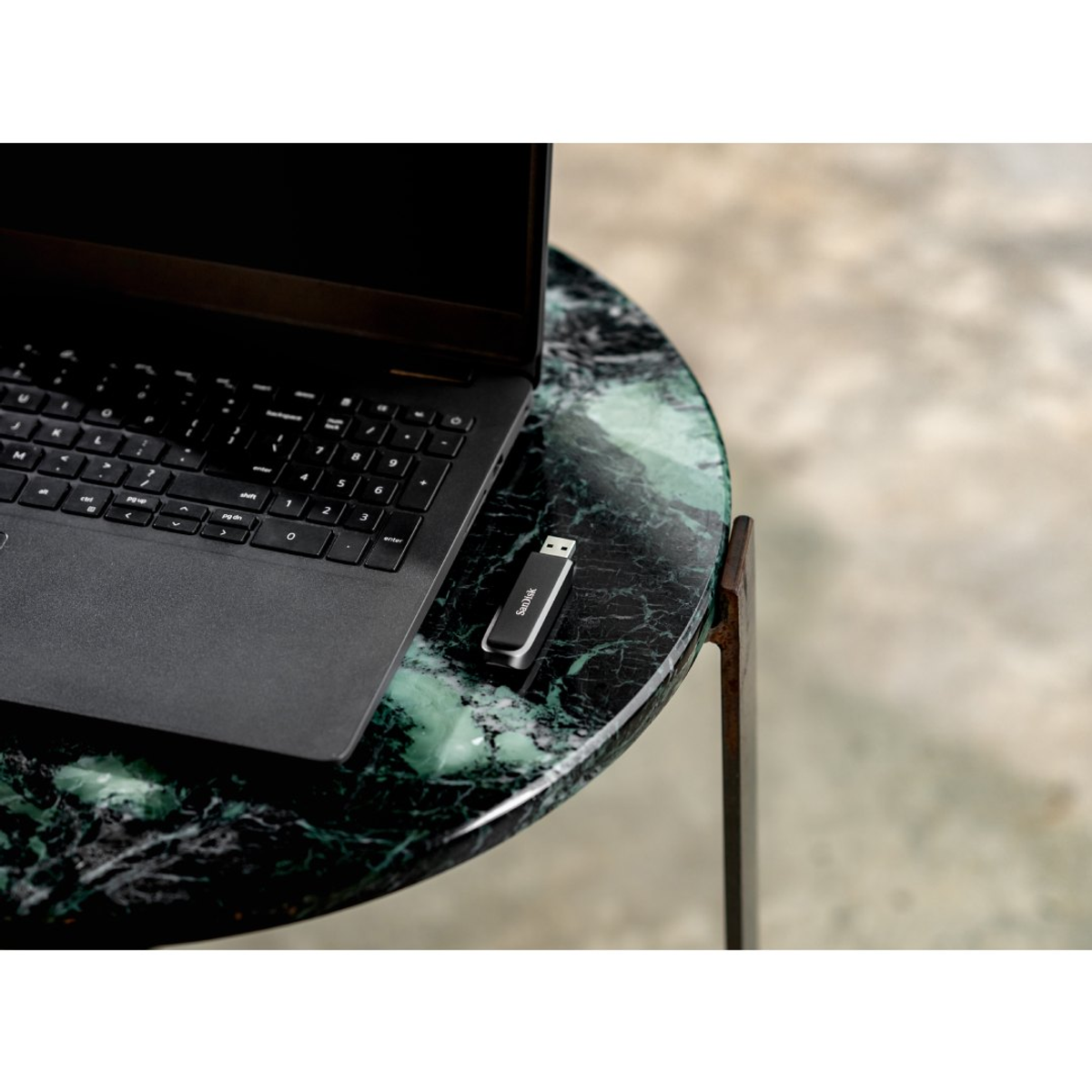 Un'unità USB accanto a un laptop nero su un tavolo di marmo.