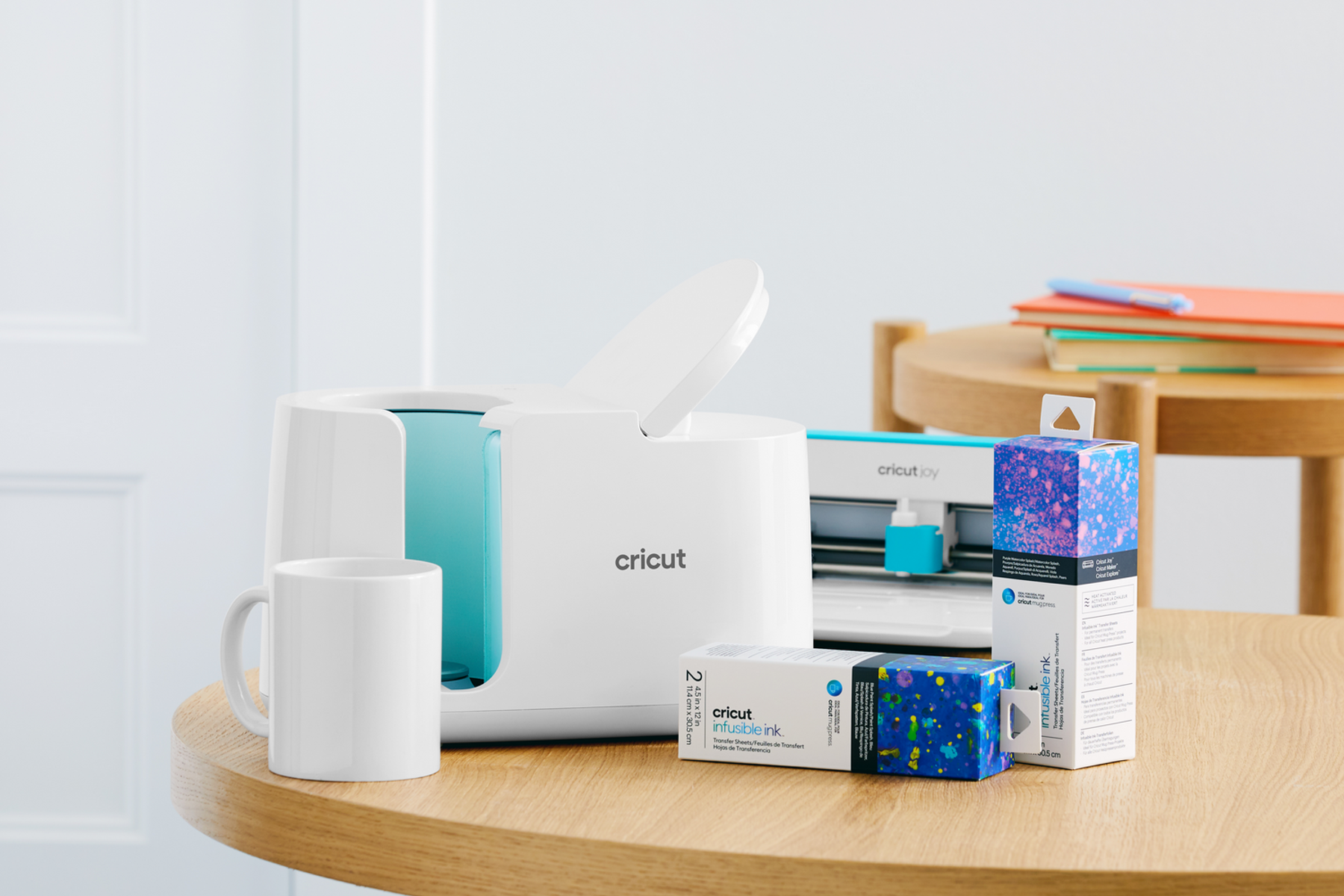 Prensa para tazas Cricut blanca, taza y cajas de tinta infusible en mesa de madera.