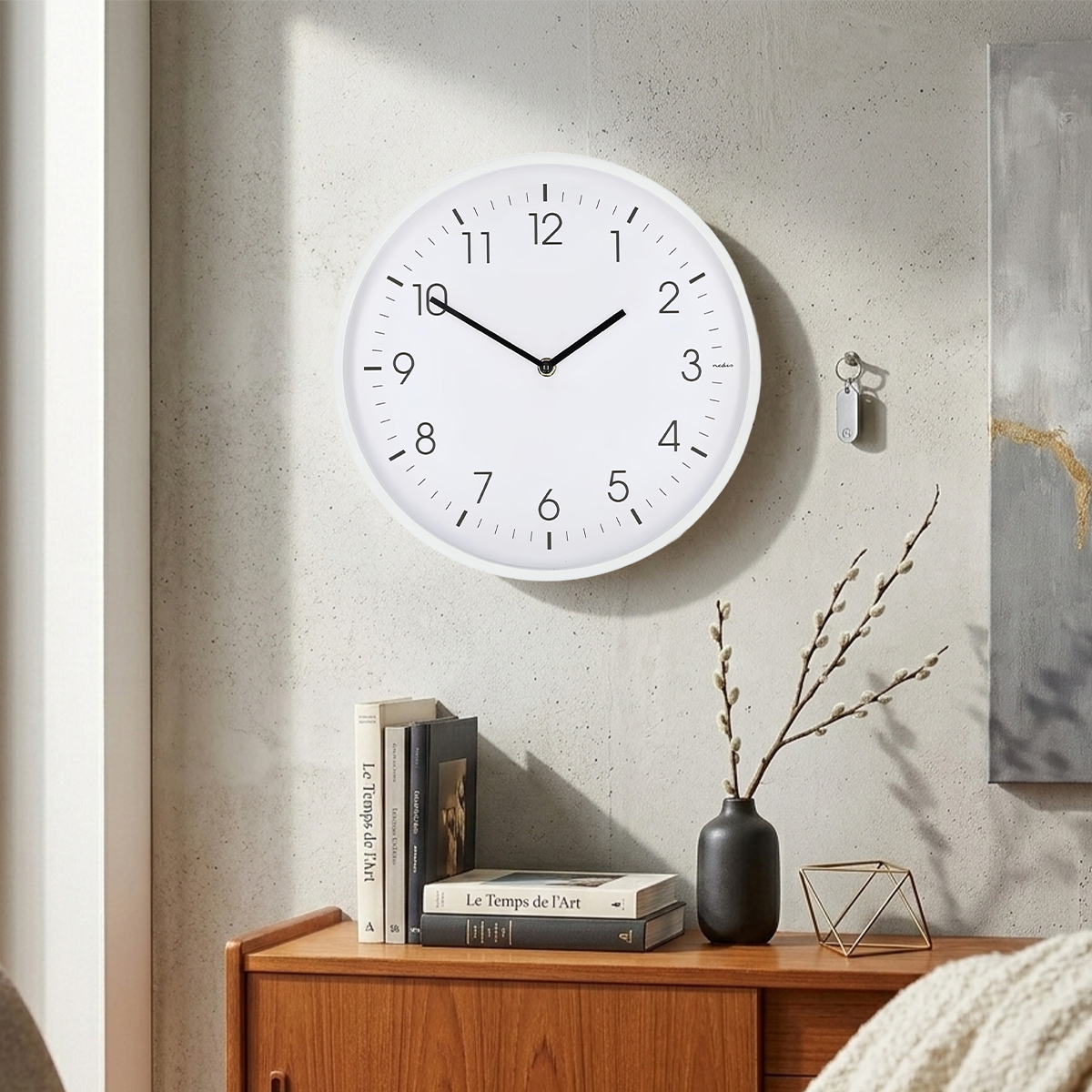 Weiße Wanduhr mit schwarzen Ziffern und Zeigern über einem Holzschrank.