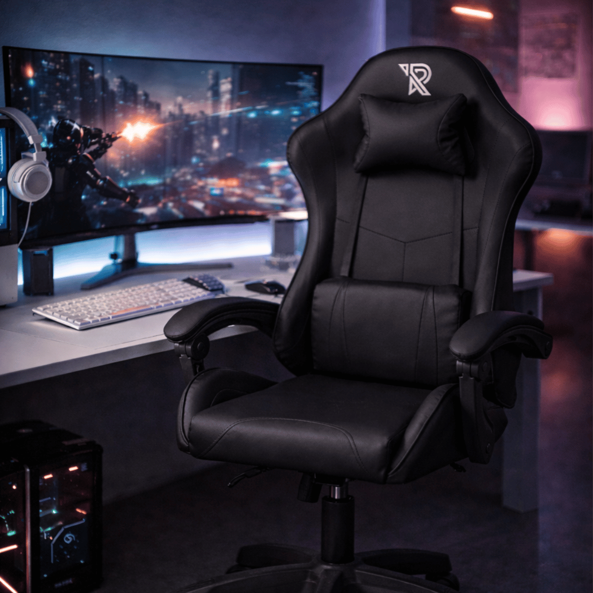 A black gaming chair sits in front of a desk with a monitor and keyboard.