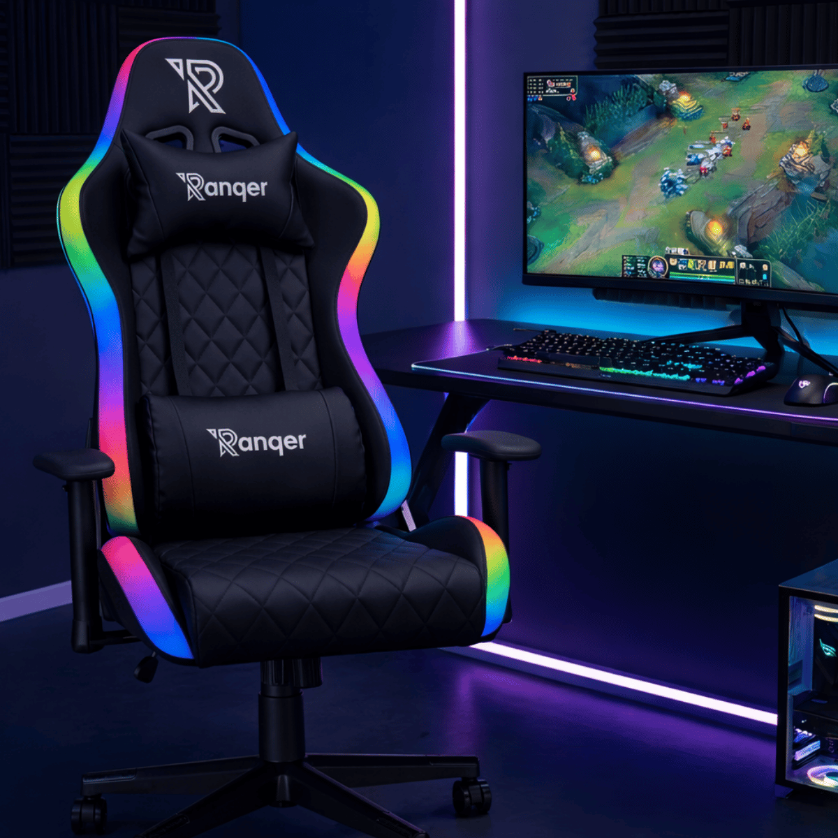 Een zwarte gamestoel met regenboog LED-verlichting naast een bureau met computer.