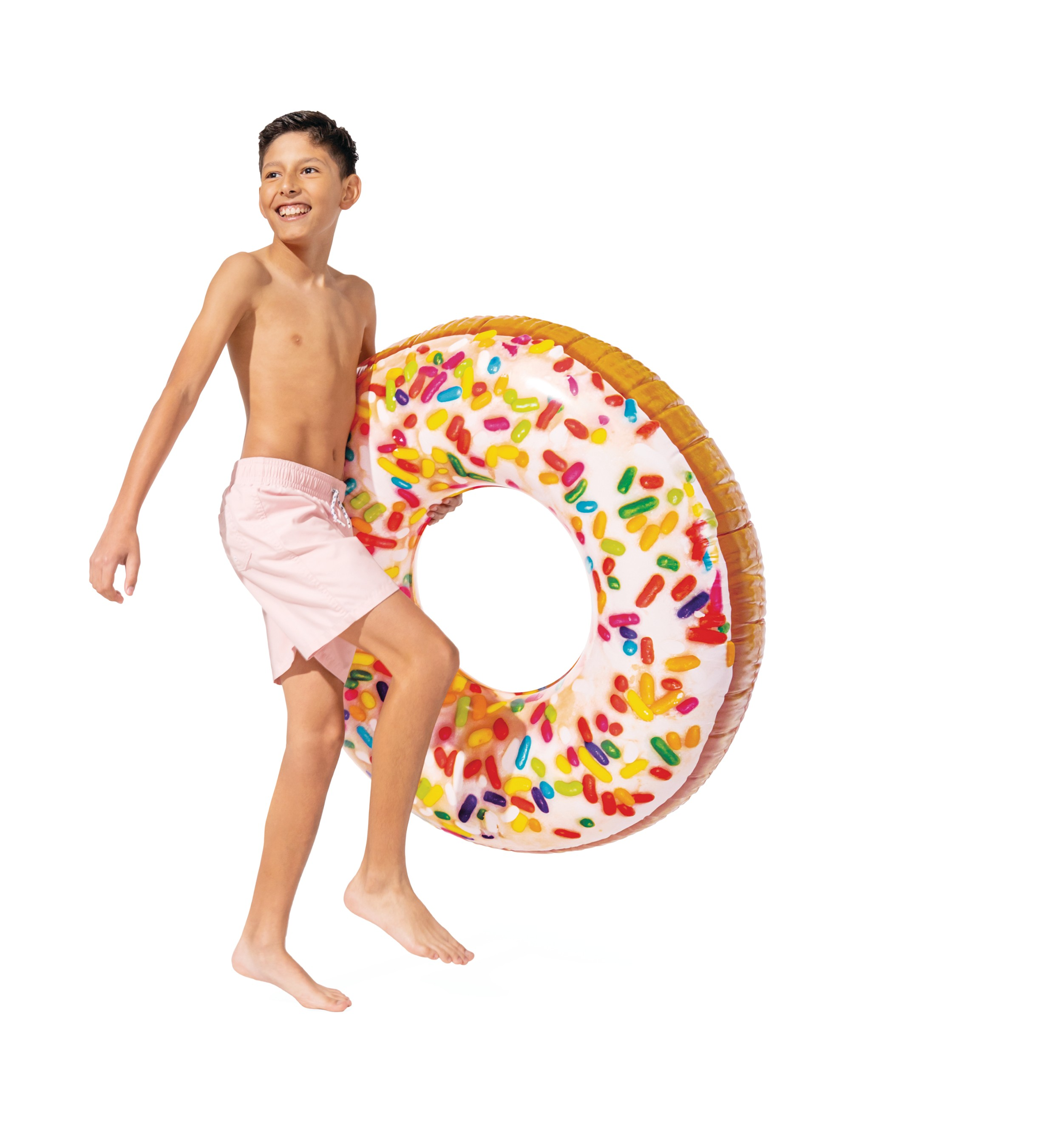 Chłopiec w różowych spodenkach pływackich niesie dmuchany donut.