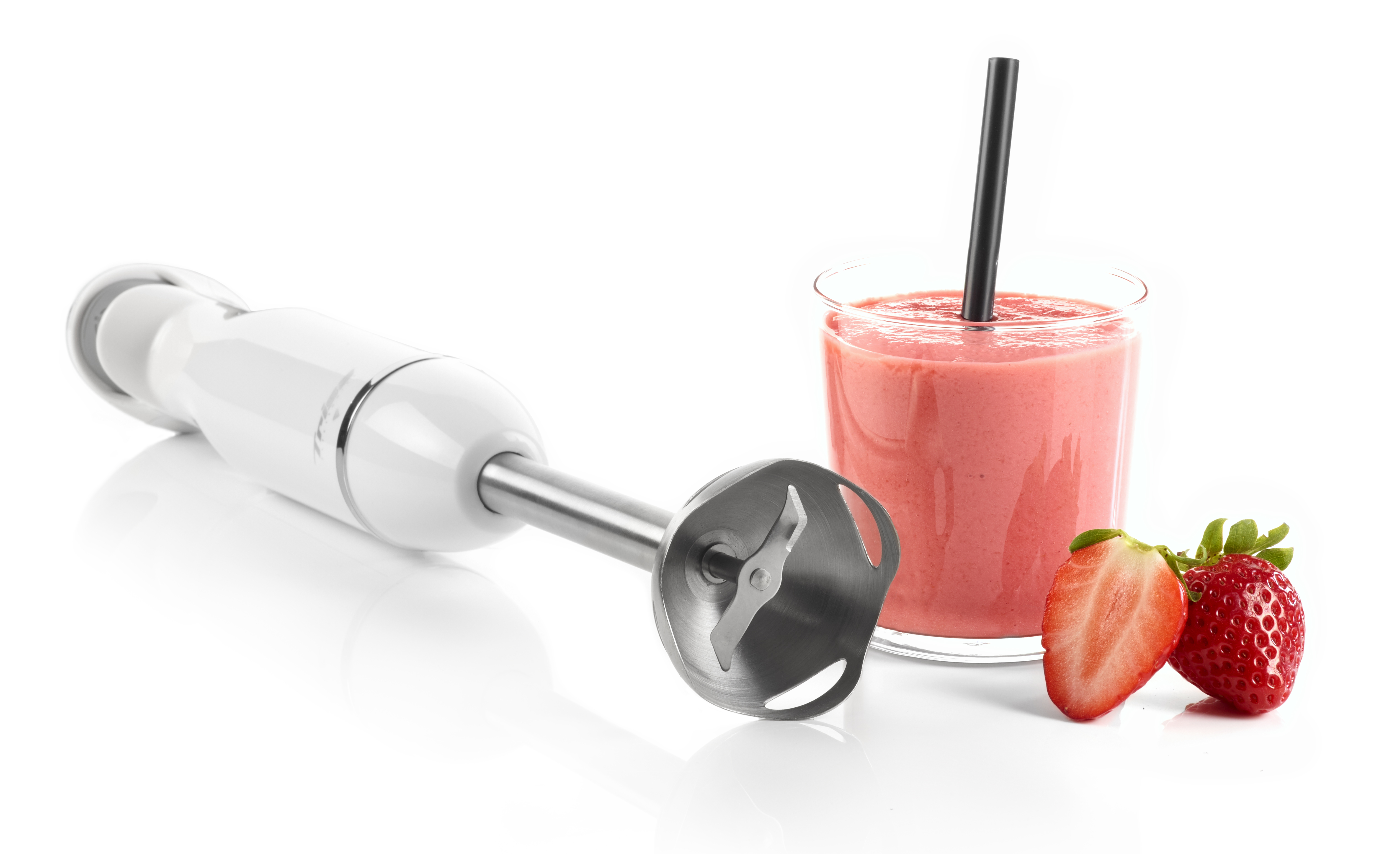Ein weißer Stabmixer liegt neben einem Glas Erdbeer-Smoothie mit Strohhalm.