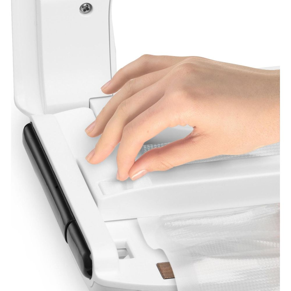 Eine Hand platziert einen Vakuumbeutel in einer weißen Versiegelungsmaschine.