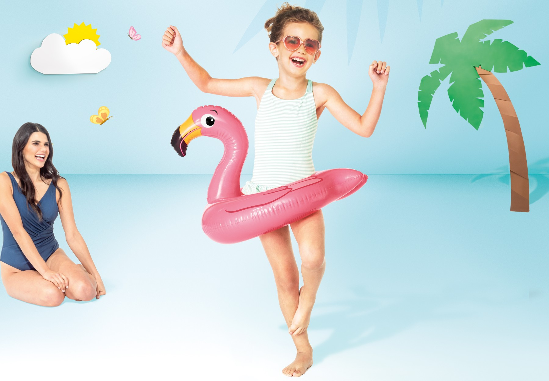 Dziewczynka z dmuchanym flamingiem i kobieta w niebieskim stroju kąpielowym na plaży.