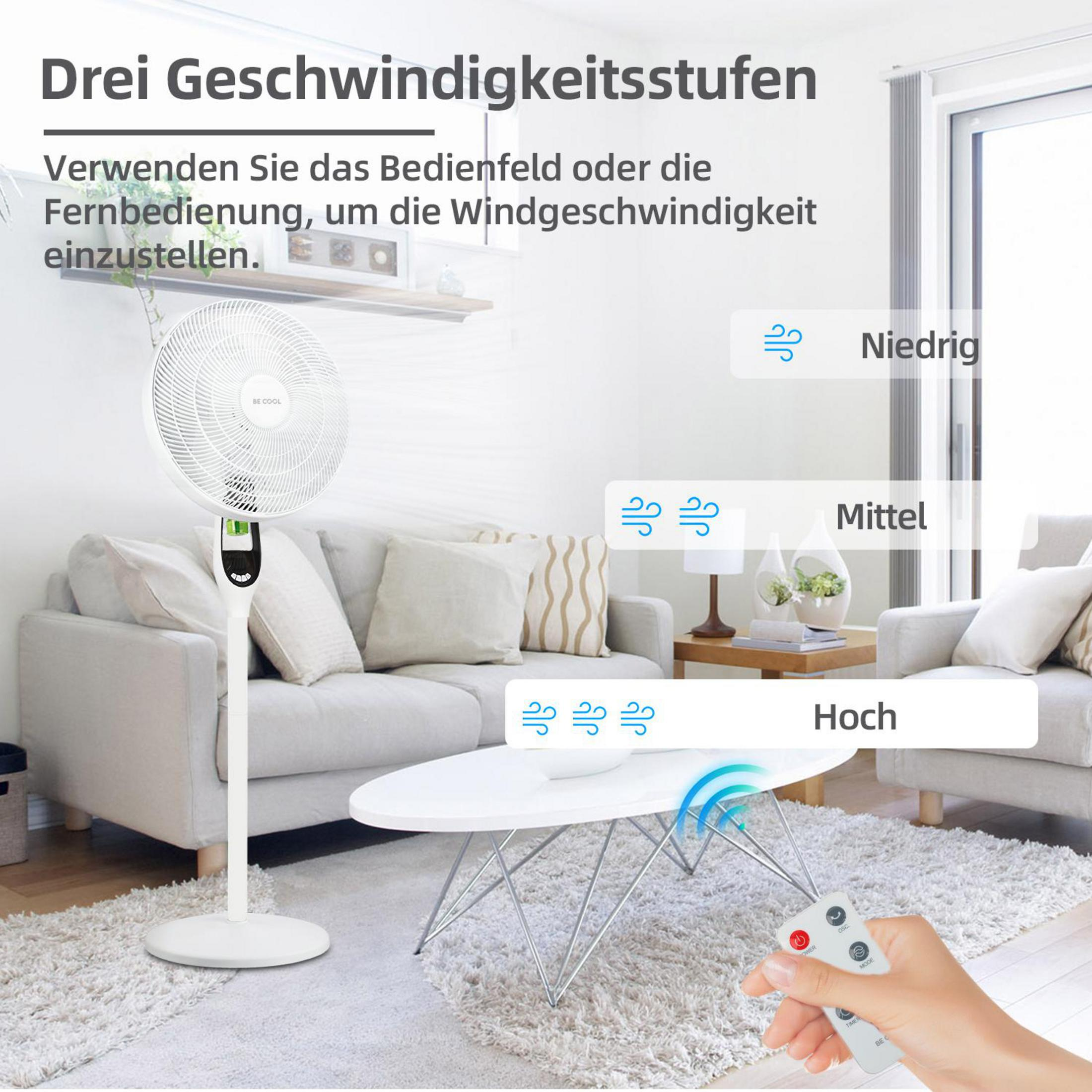 Un ventilatore da terra bianco si trova in un soggiorno. È visibile un telecomando.