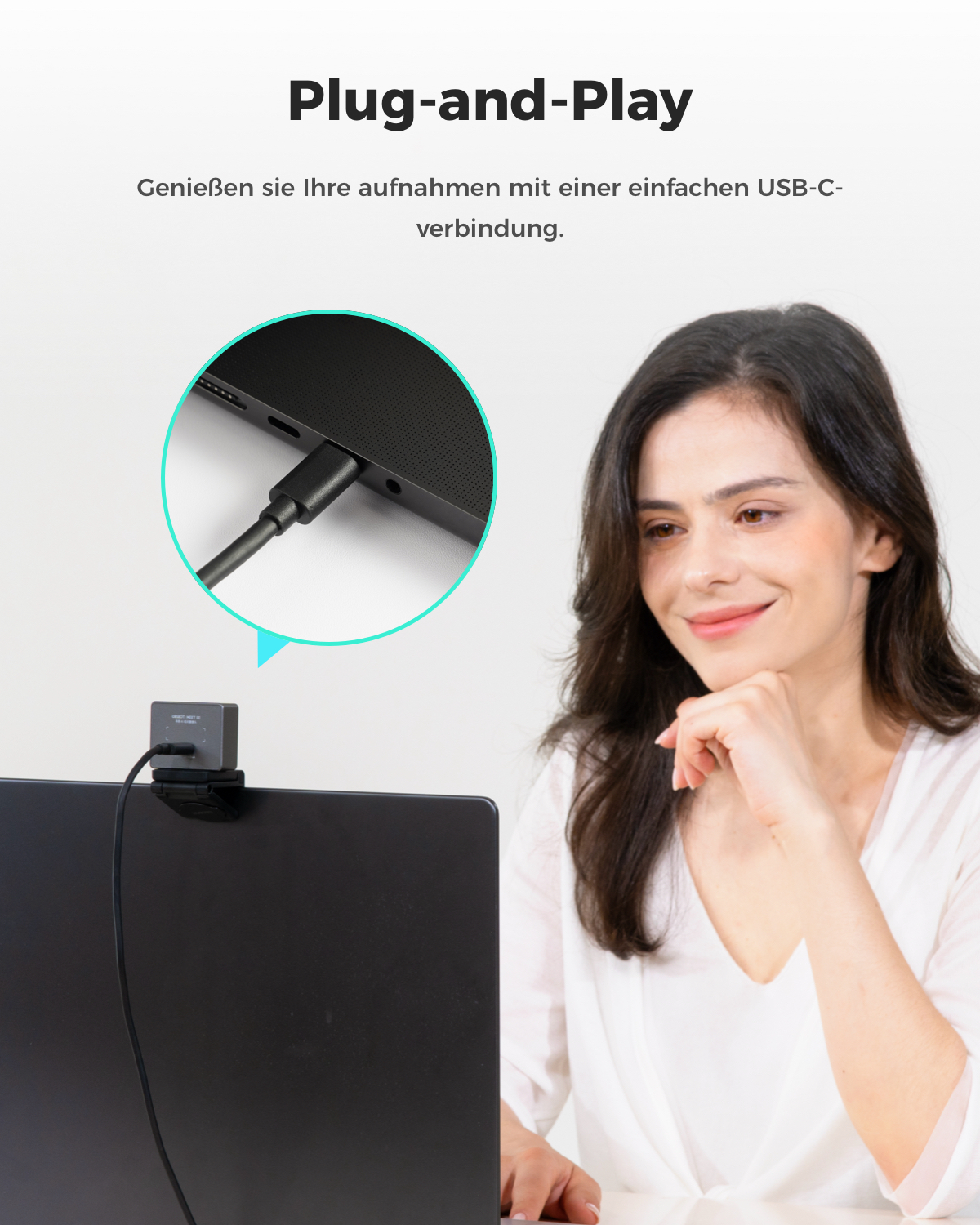 Eine Frau sitzt vor einem Laptop, auf dem eine Webcam montiert ist. Ein USB-C-Kabel wird angeschlossen.