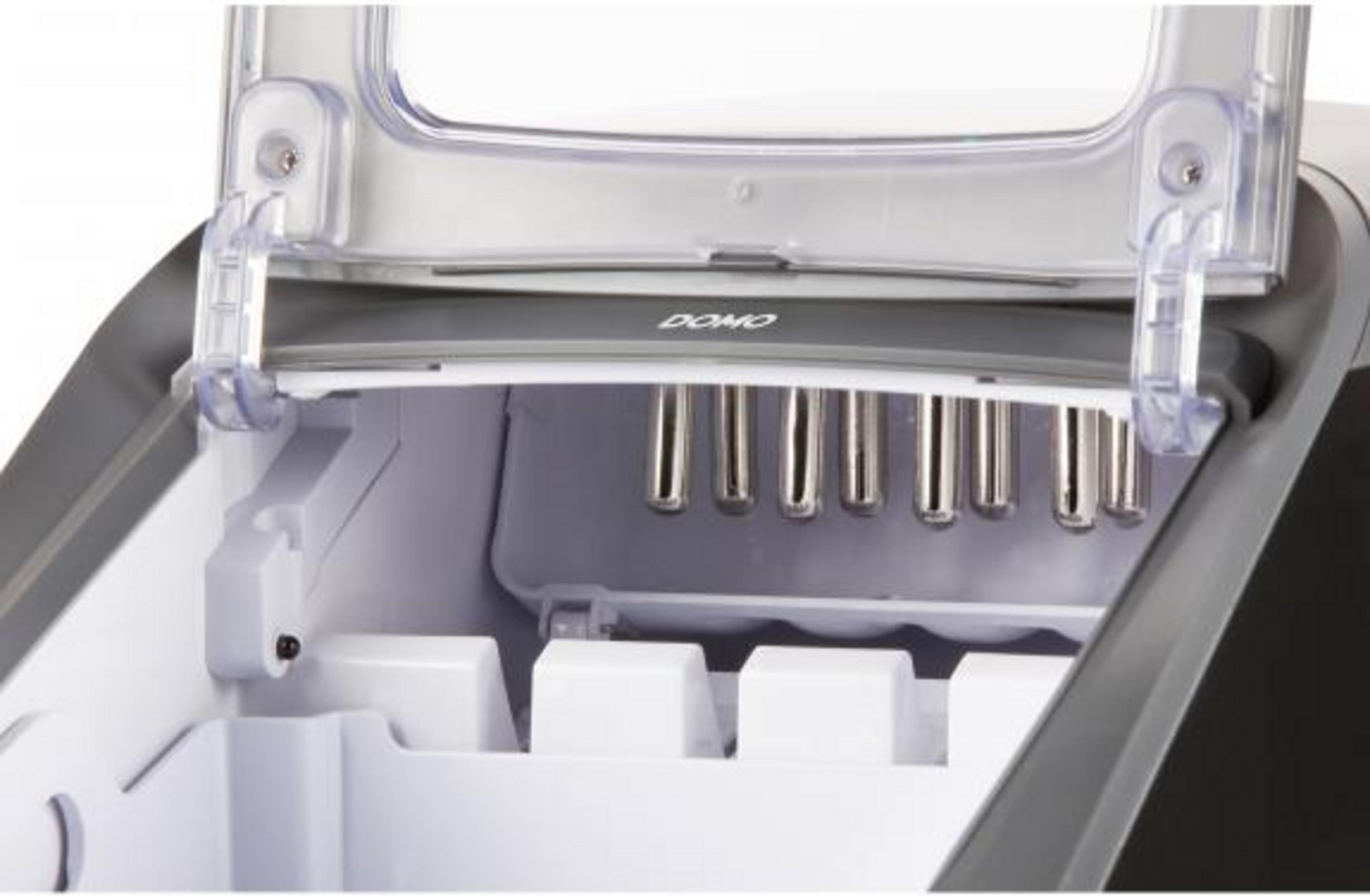 Wnętrze kostkarki do lodu ze srebrnymi rurkami i białymi przegrodami.