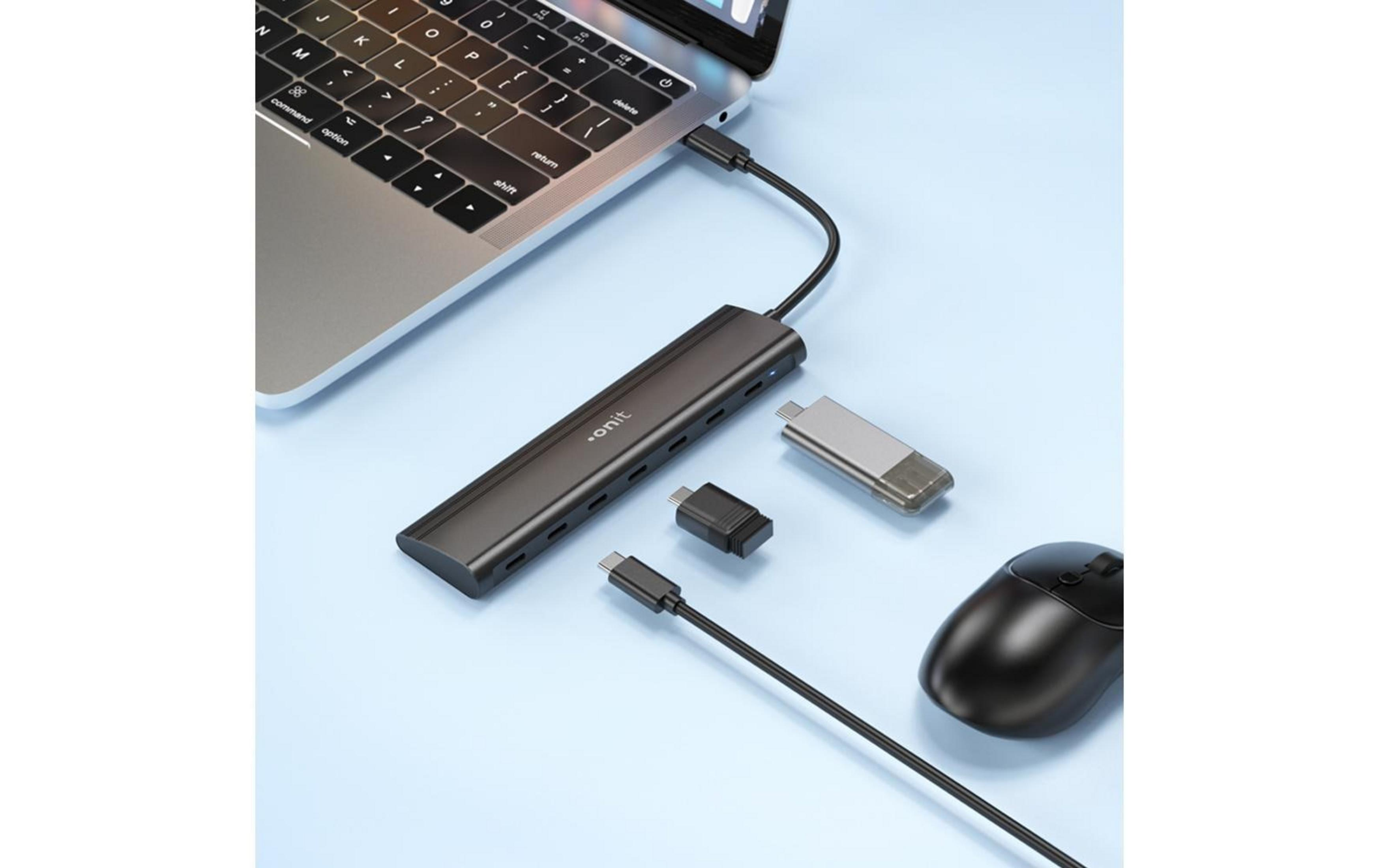 Ein schwarzer USB-C-Hub ist an einen Laptop angeschlossen, daneben liegen eine Maus und Adapter.