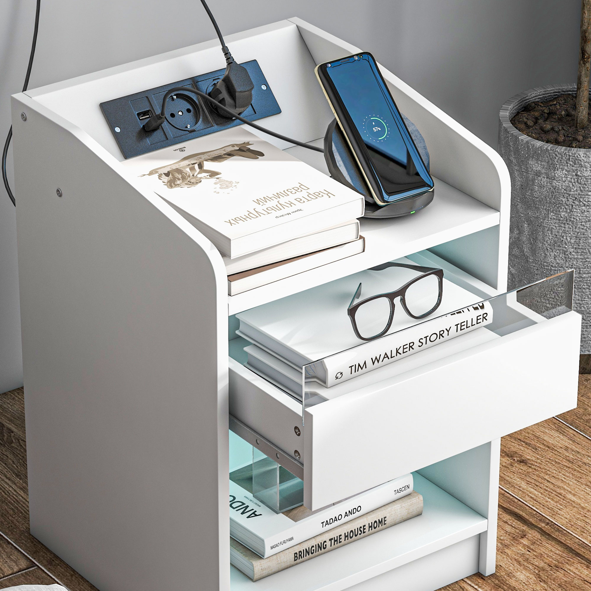 Mesita de noche blanca con libros, gafas, teléfono y regleta.