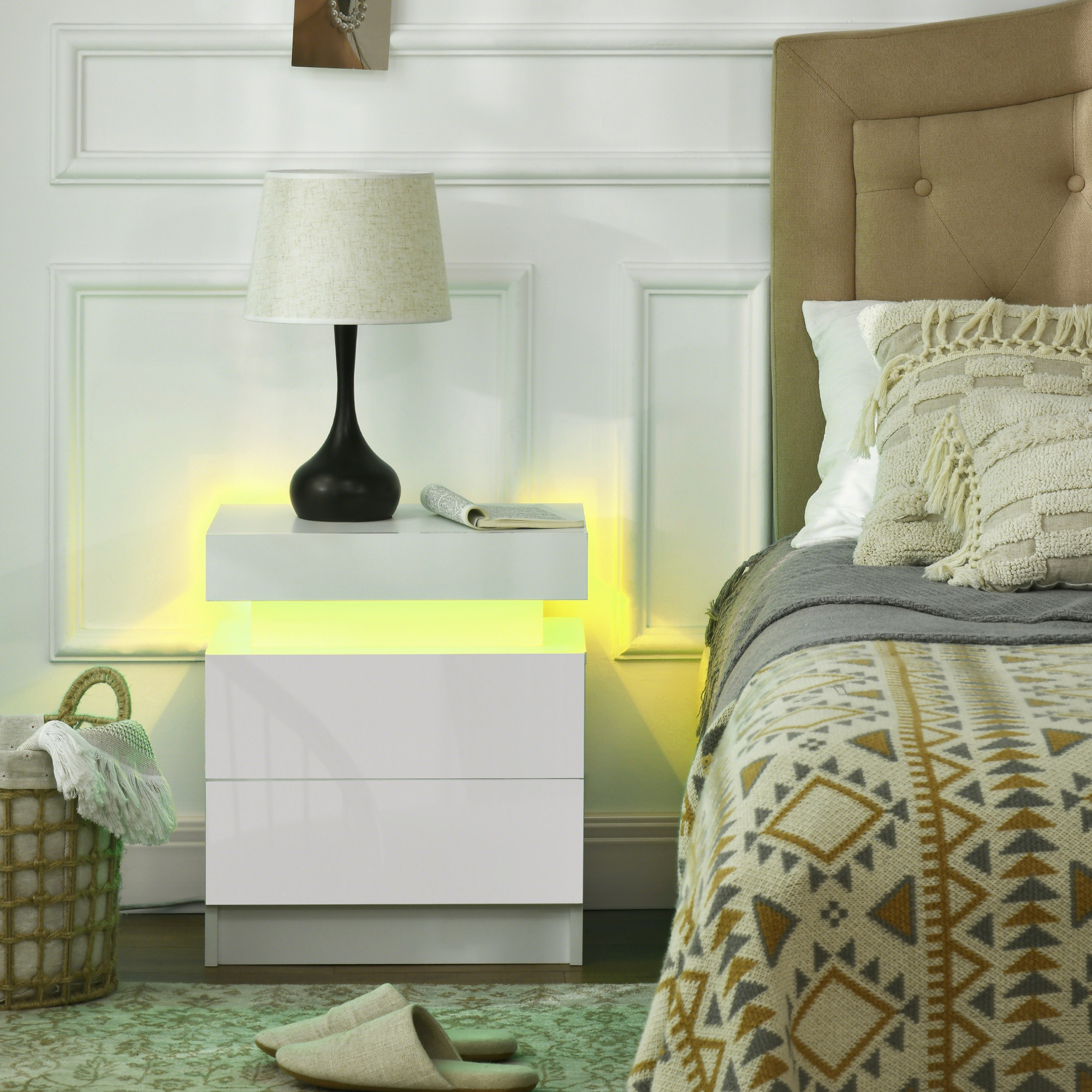 Una mesita de noche blanca con luz LED amarilla junto a una cama.