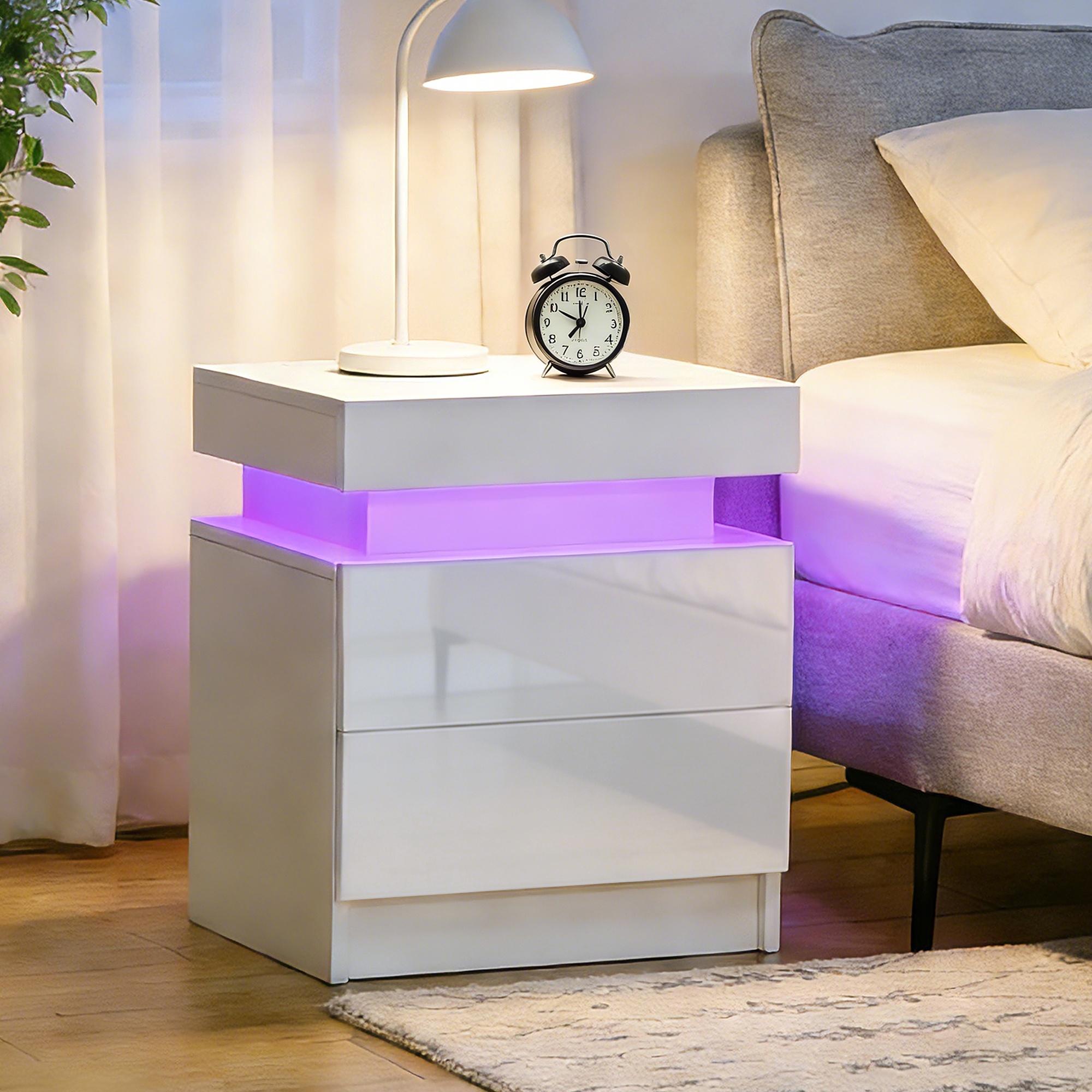 Una mesita de noche blanca con iluminación púrpura junto a una cama.