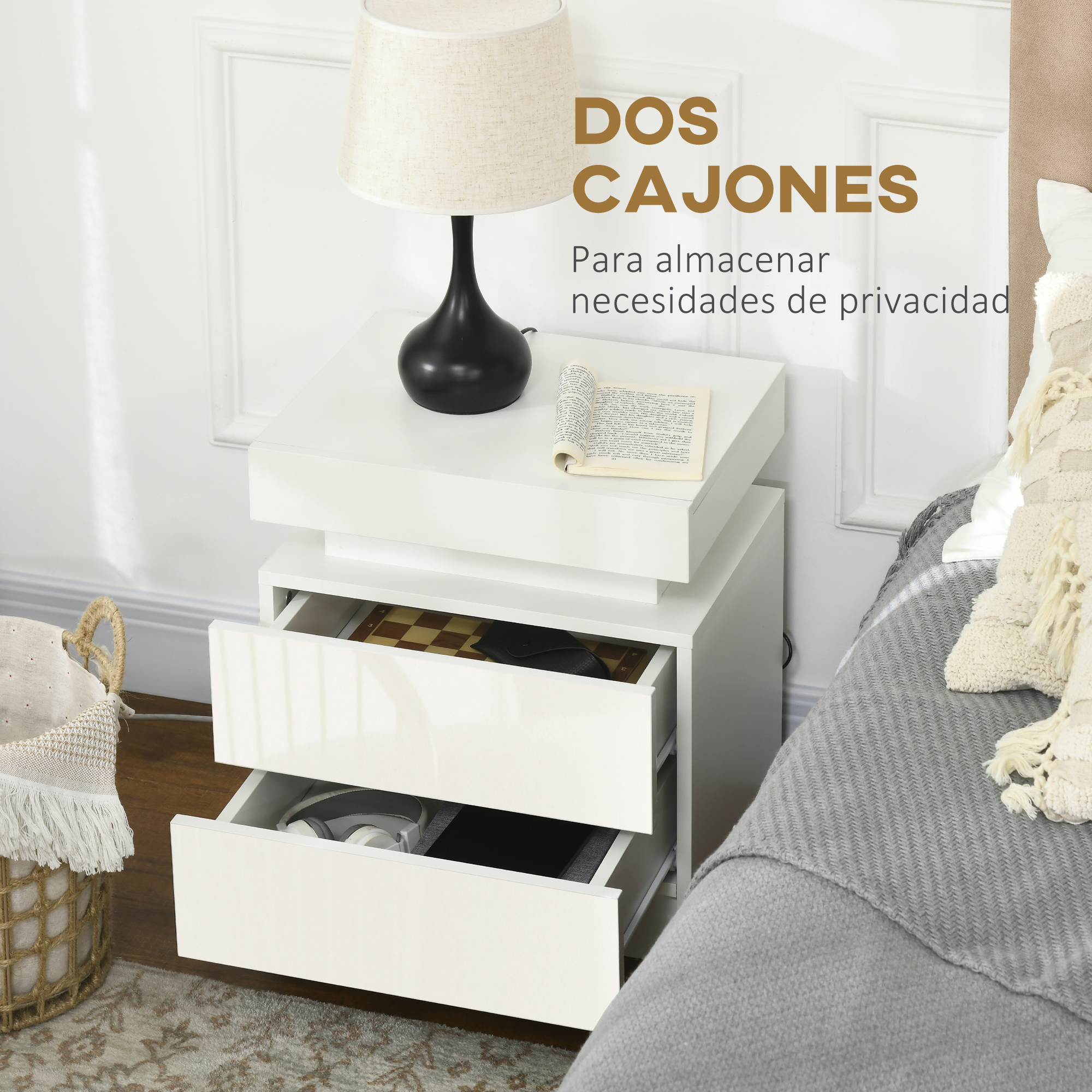 Mesita de noche blanca con cajones abiertos, lámpara, libro y cesta.