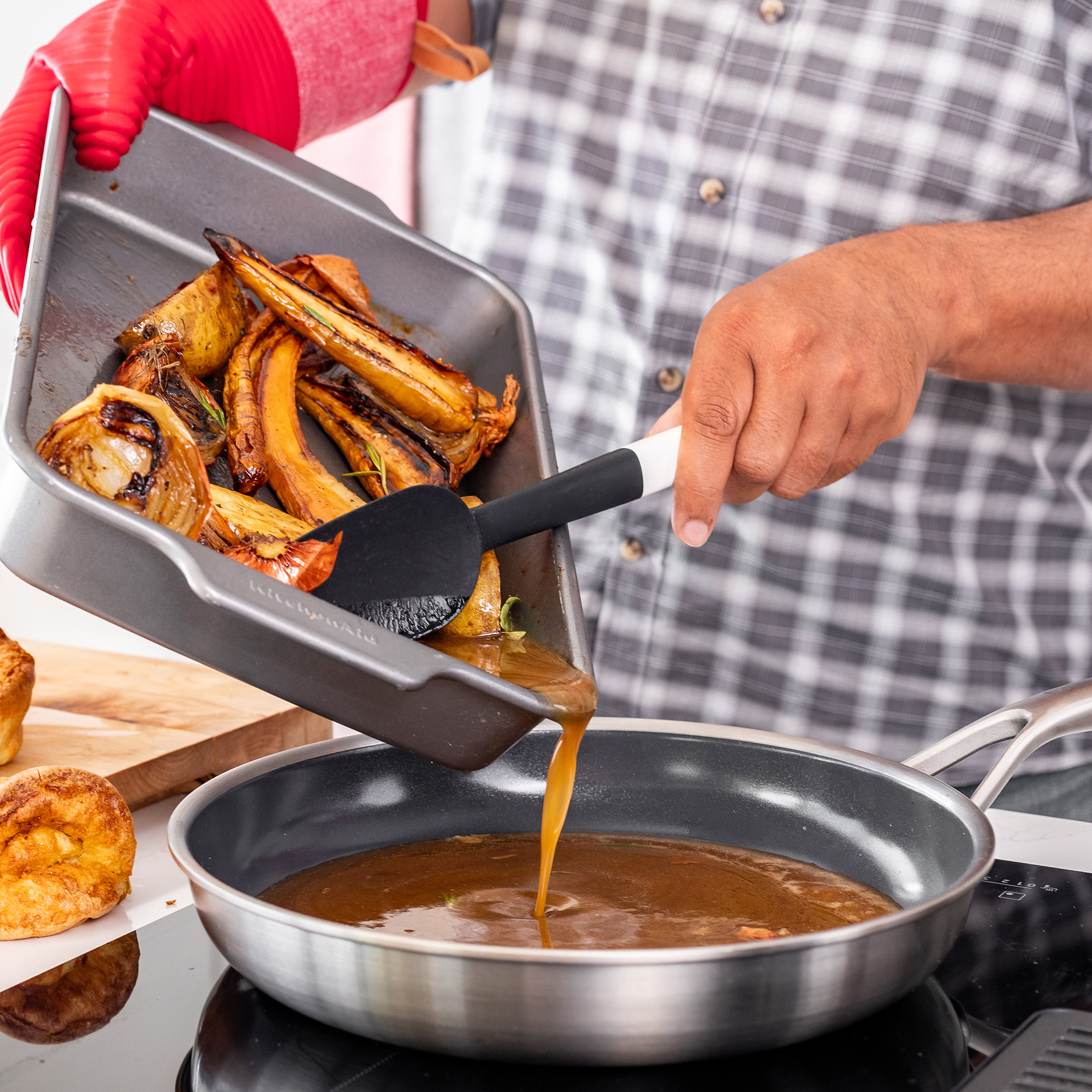 Geröstetes Gemüse wird aus einer Schale in eine Pfanne mit Soße gegossen.
