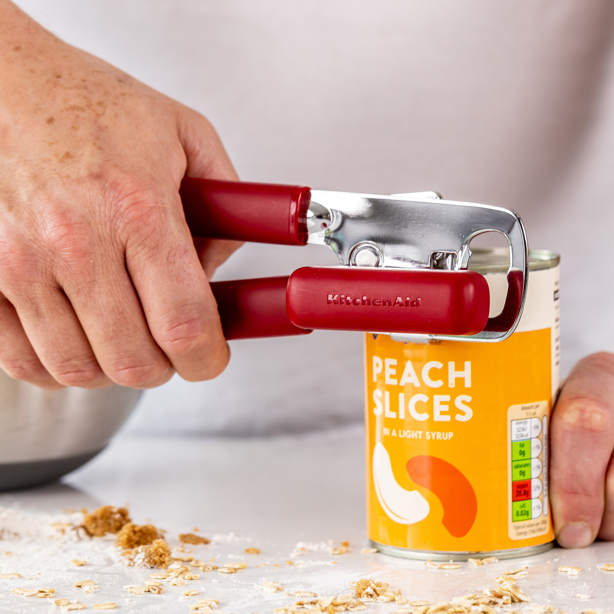 Eine rote KitchenAid-Dosenöffner öffnet eine Dose Pfirsichscheiben.