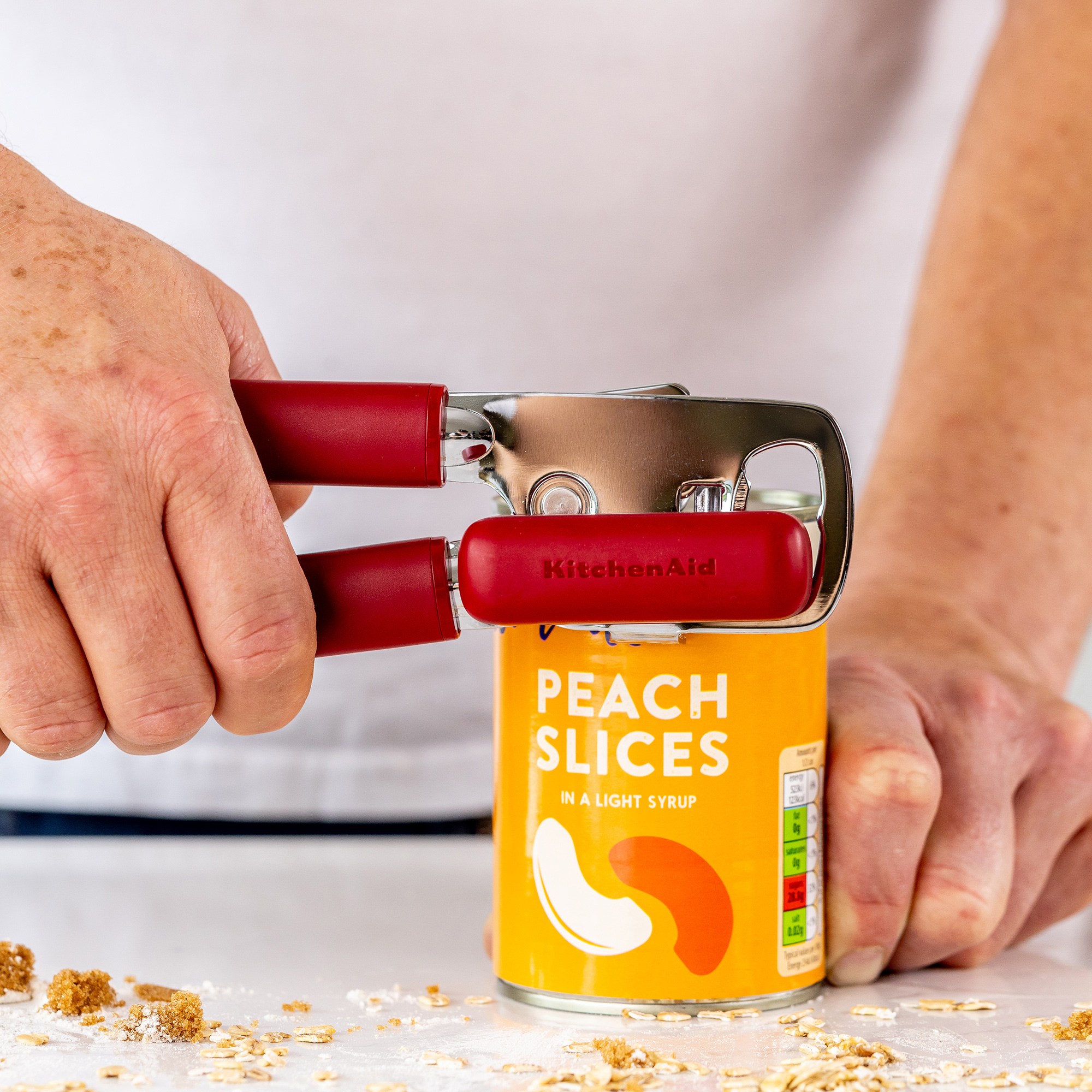 Rote Küchenmaschine öffnet eine Dose Pfirsichspalten in leichtem Sirup.