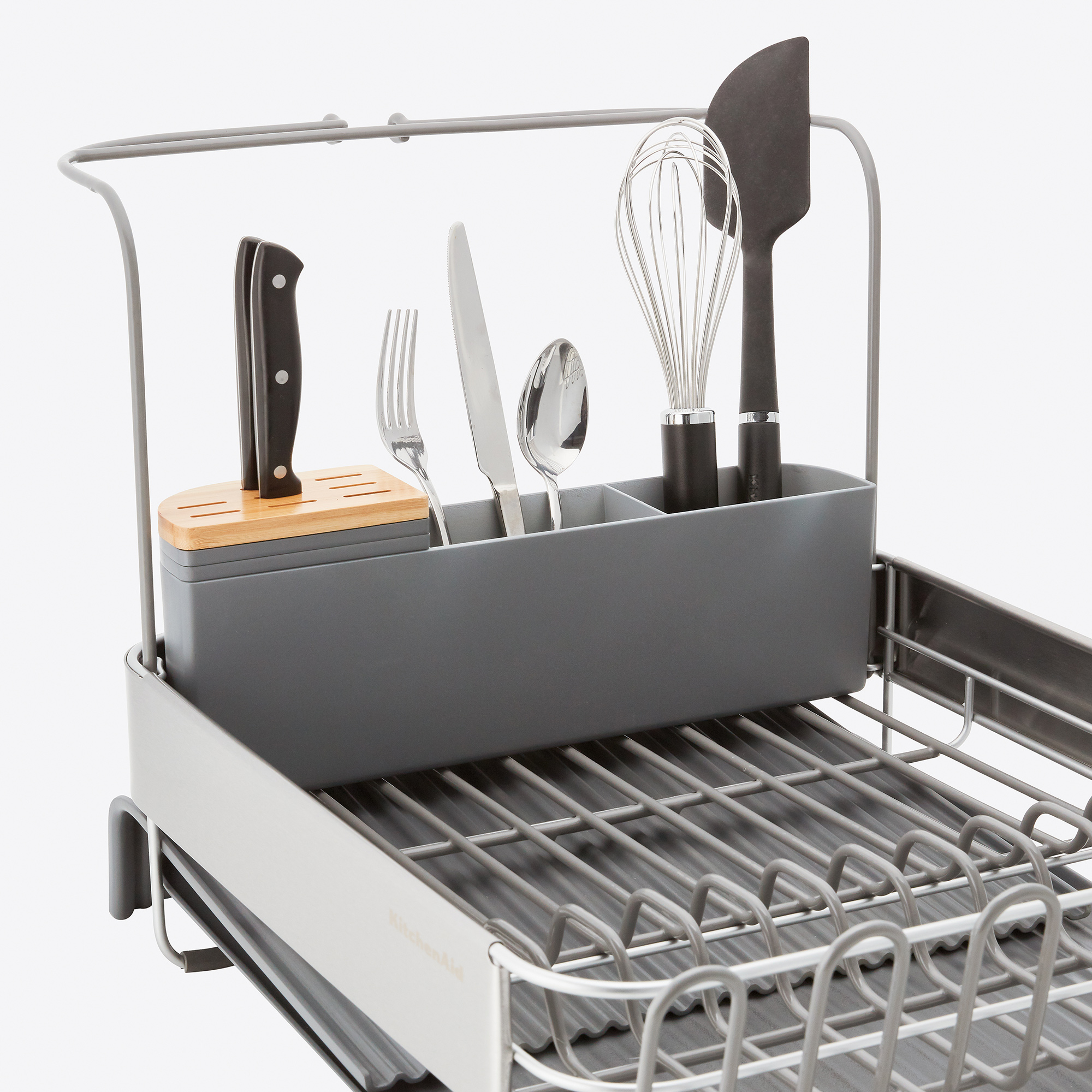 Ein grauer Abtropfgestell mit Küchenutensilien, darunter Messer, Gabel, Löffel, Schneebesen und Spatel.