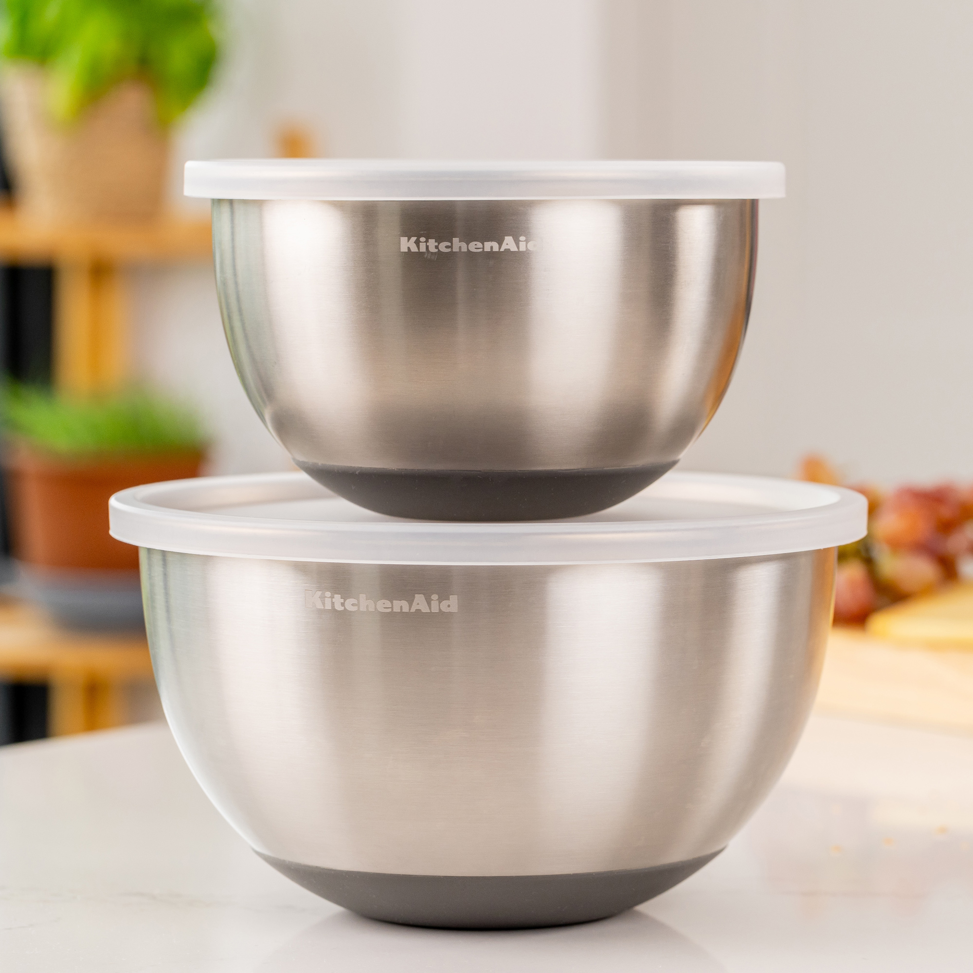 Zwei KitchenAid-Schüsseln aus Edelstahl mit weißen Deckeln, gestapelt.