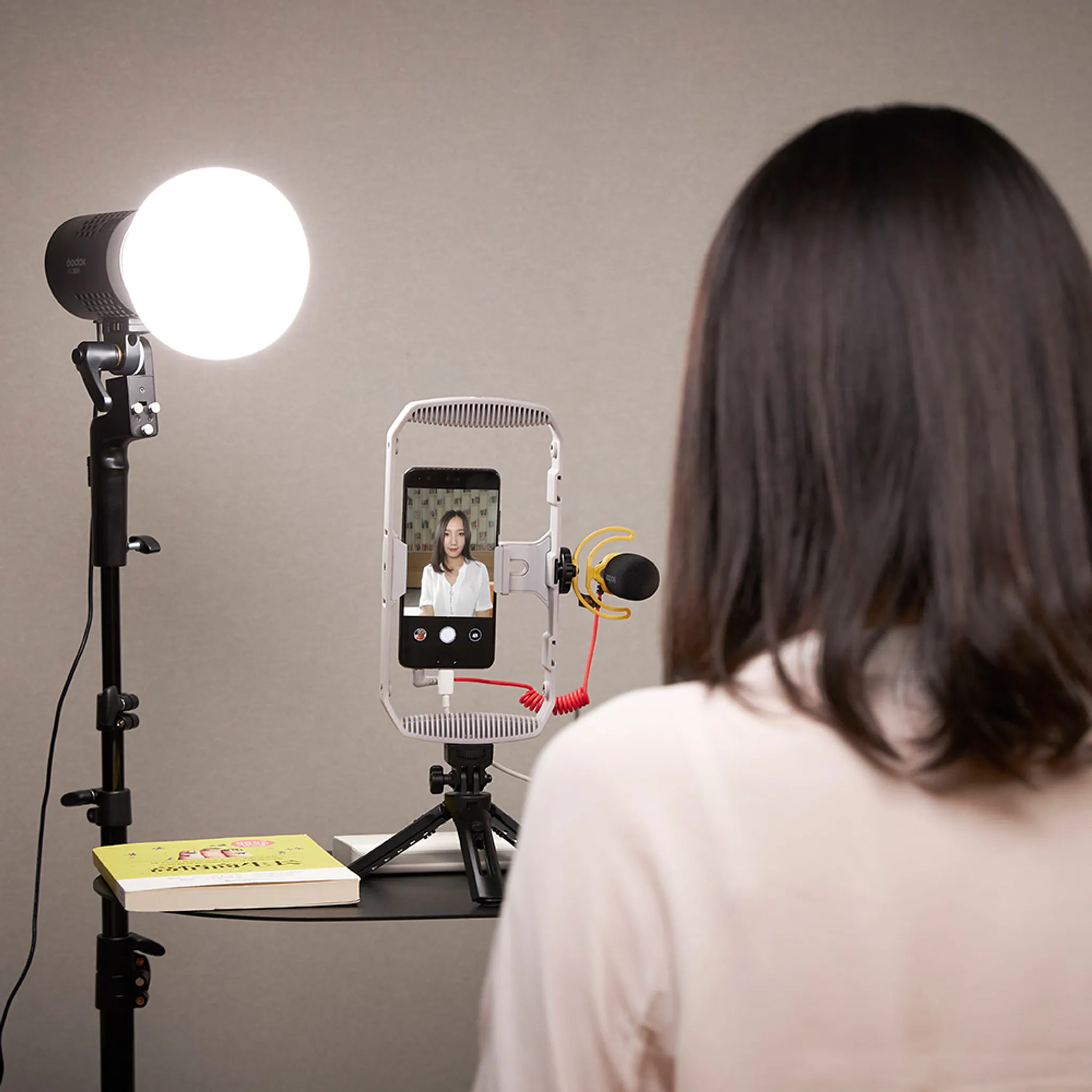 Eine Frau filmt sich mit einer Handy-Rig, Mikrofon und Licht.