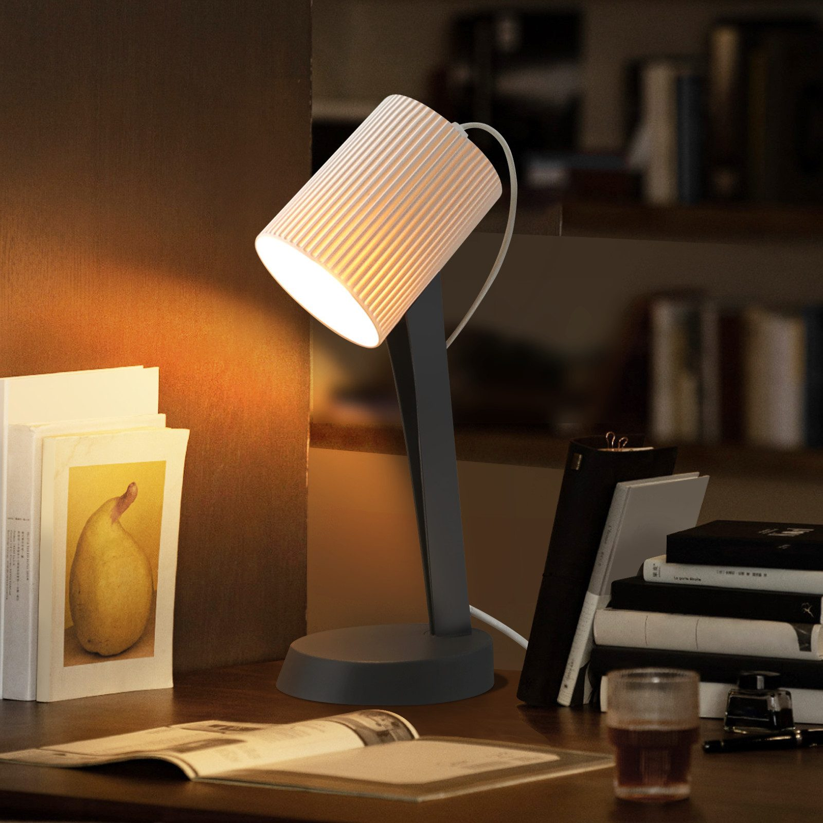 Una scrivania con lampada, libri e un bicchiere di bevanda.
