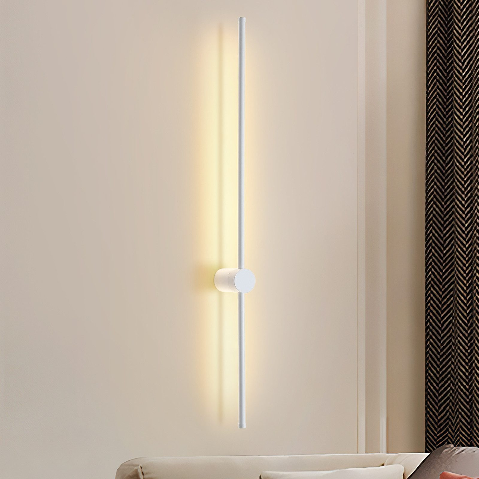 Una lámpara de pared blanca y elegante con luz cálida ilumina una pared beige.