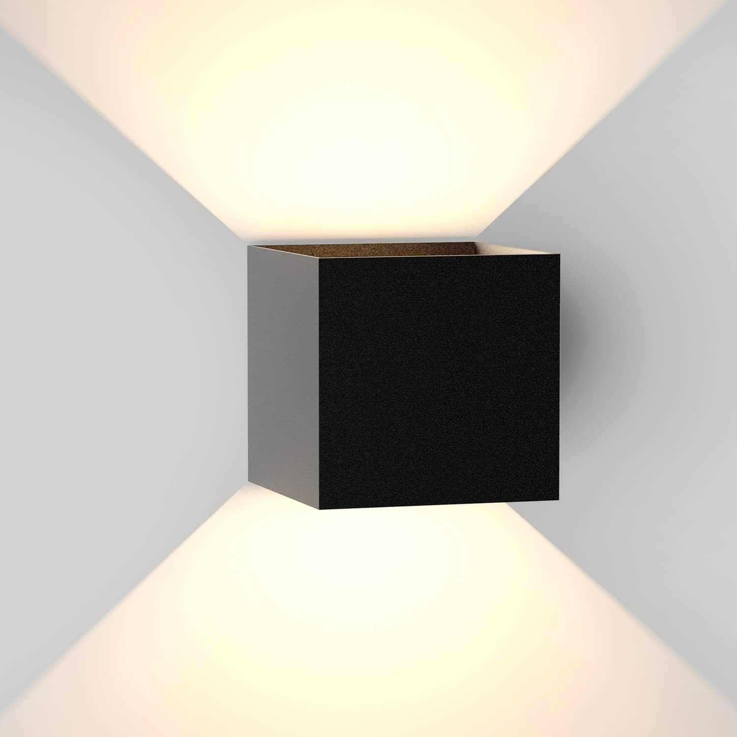 Una lámpara de pared cúbica negra ilumina hacia arriba y hacia abajo en una pared blanca.