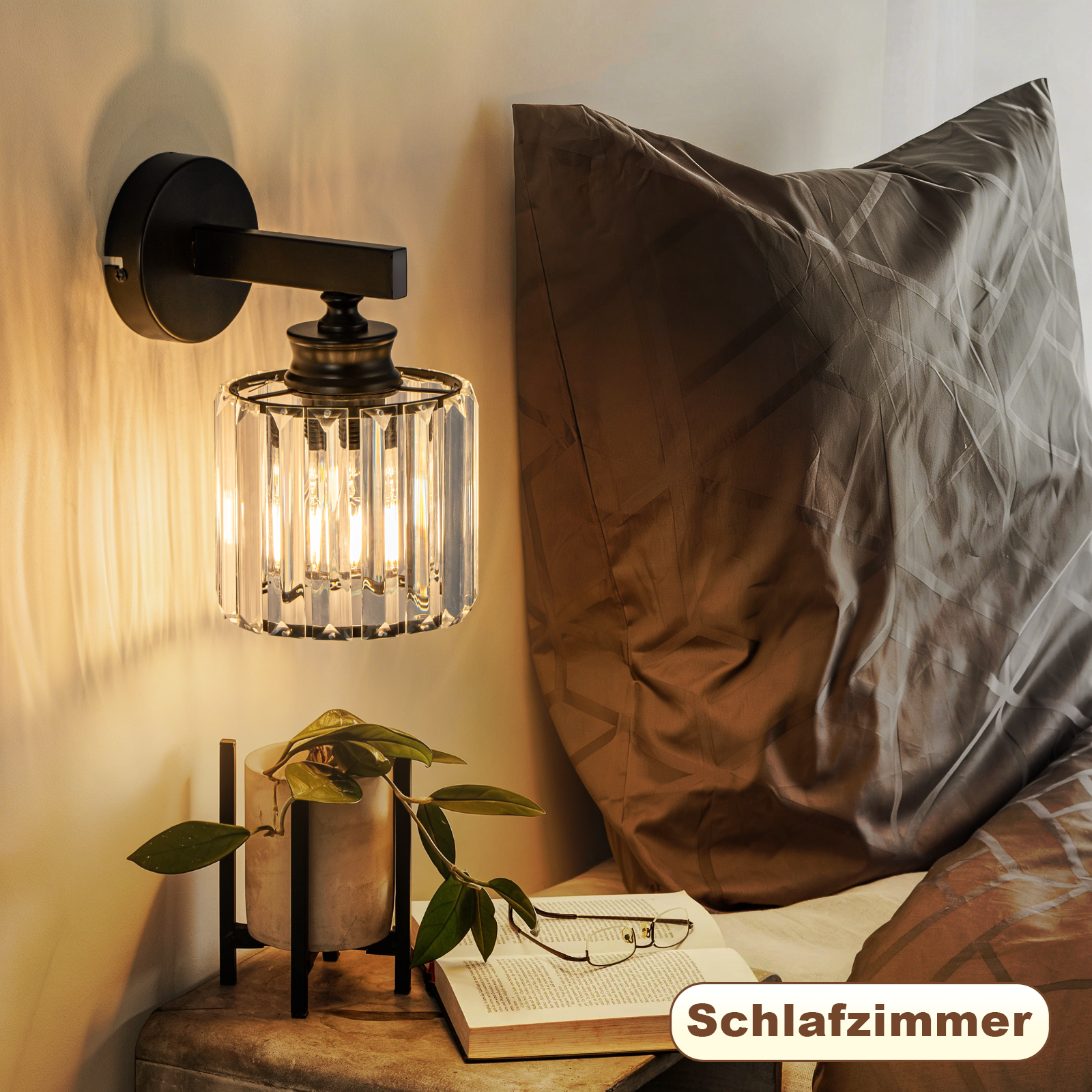 Una mesita de noche con lámpara, libro y planta junto a una cama.