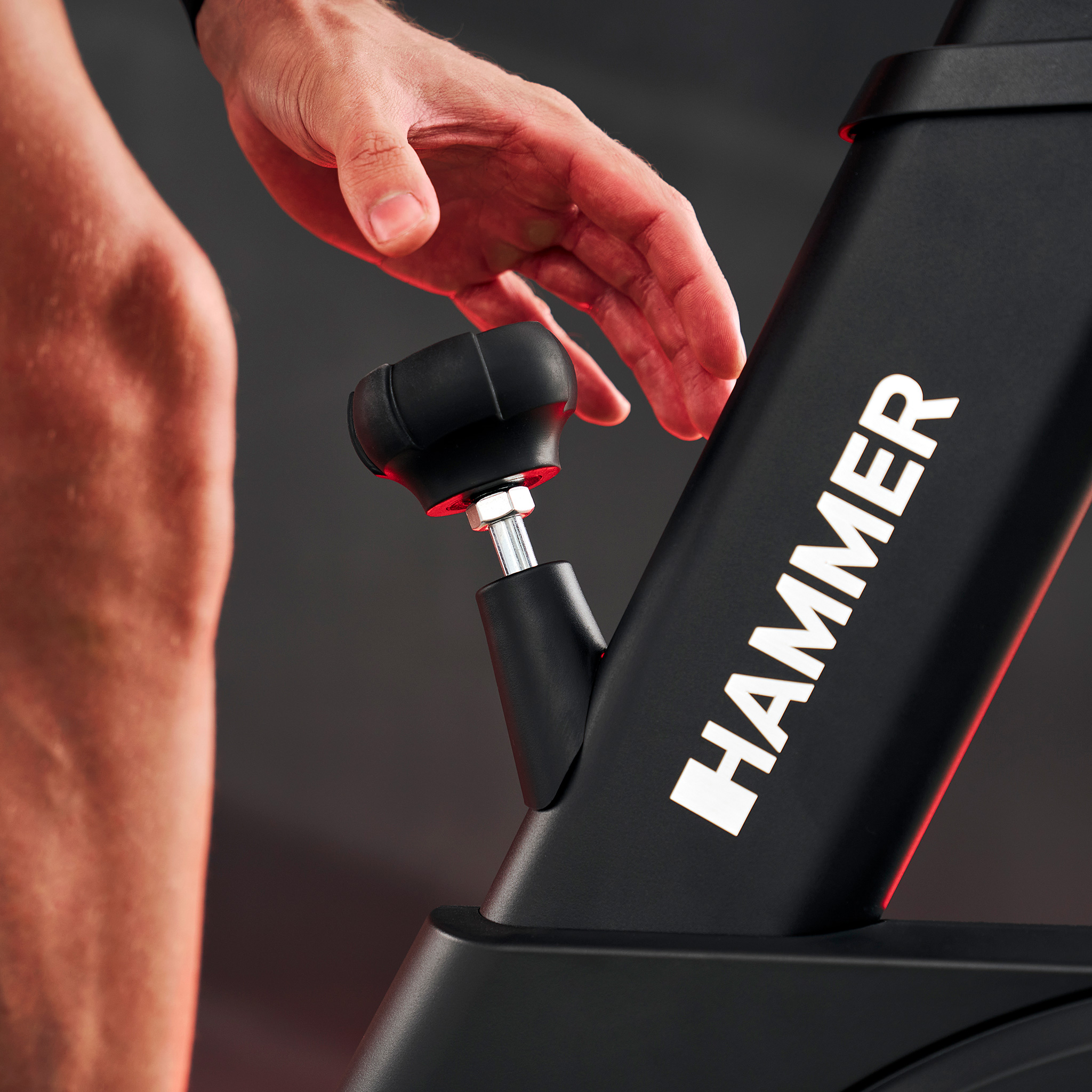 Mężczyzna reguluje opór roweru stacjonarnego.