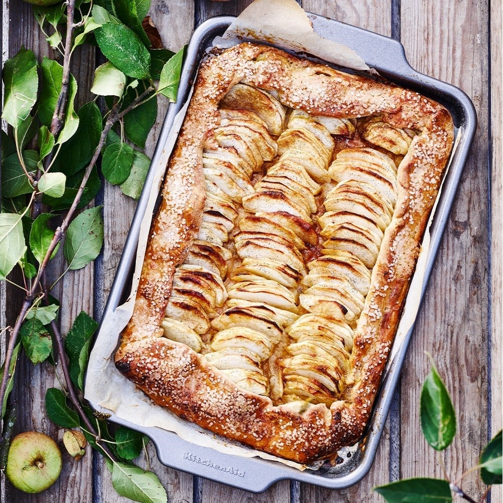 İnce dilimlenmiş elmalı, metal fırın tepsisinde pişmiş elmalı tart.